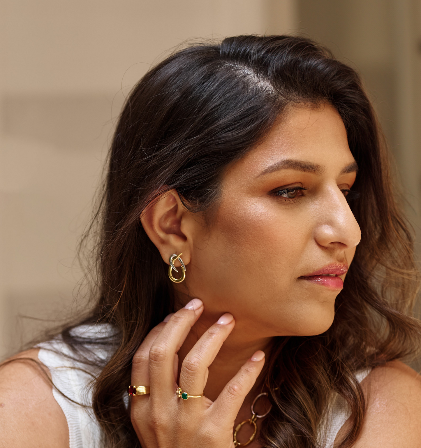 Close-up of woman wearing Syra Earrings featuring interlaced gold and silver arcs symbolizing duality and grace