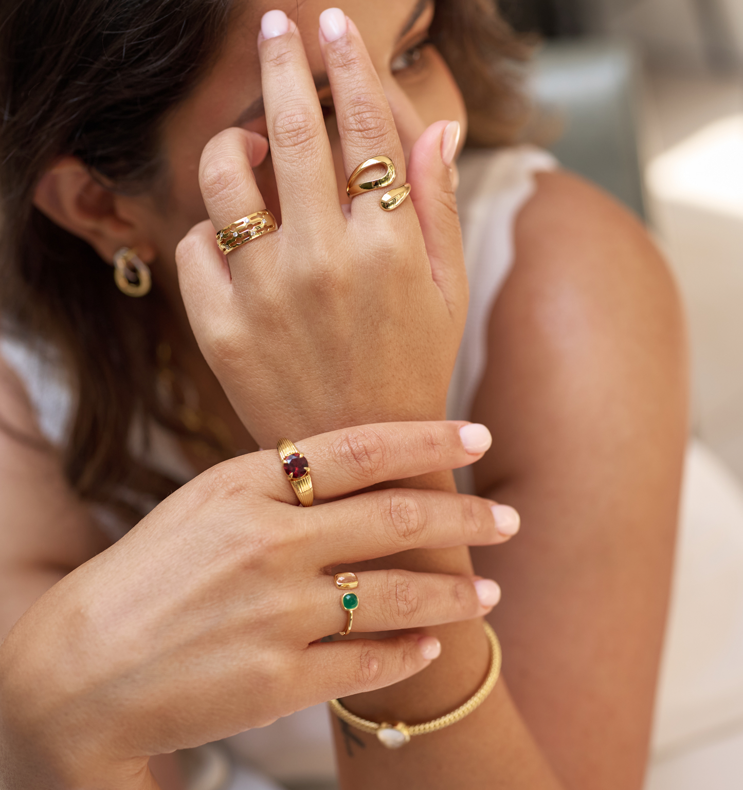 Close-up of a hand wearing multiple gold rings including the Svar Ring with seven lab-grown diamonds, showcasing elegance and clarity.