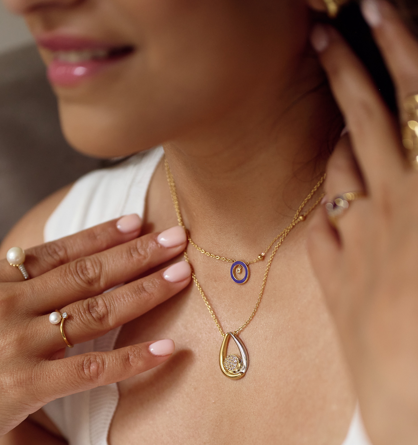 Antara Necklace with twin gold and silver arcs featuring 19 white topaz stones on a woman’s neck