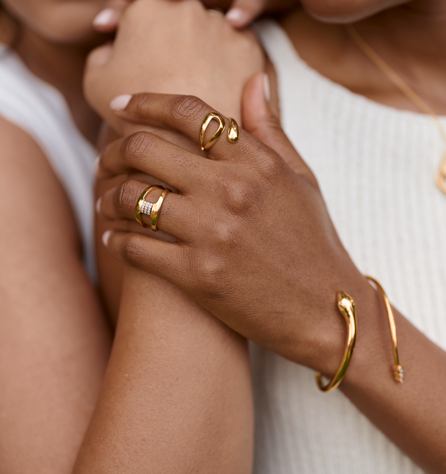 Close-up of a hand wearing the elegant gold Oriya Ring with a spiral design, paired with a matching gold bracelet.
