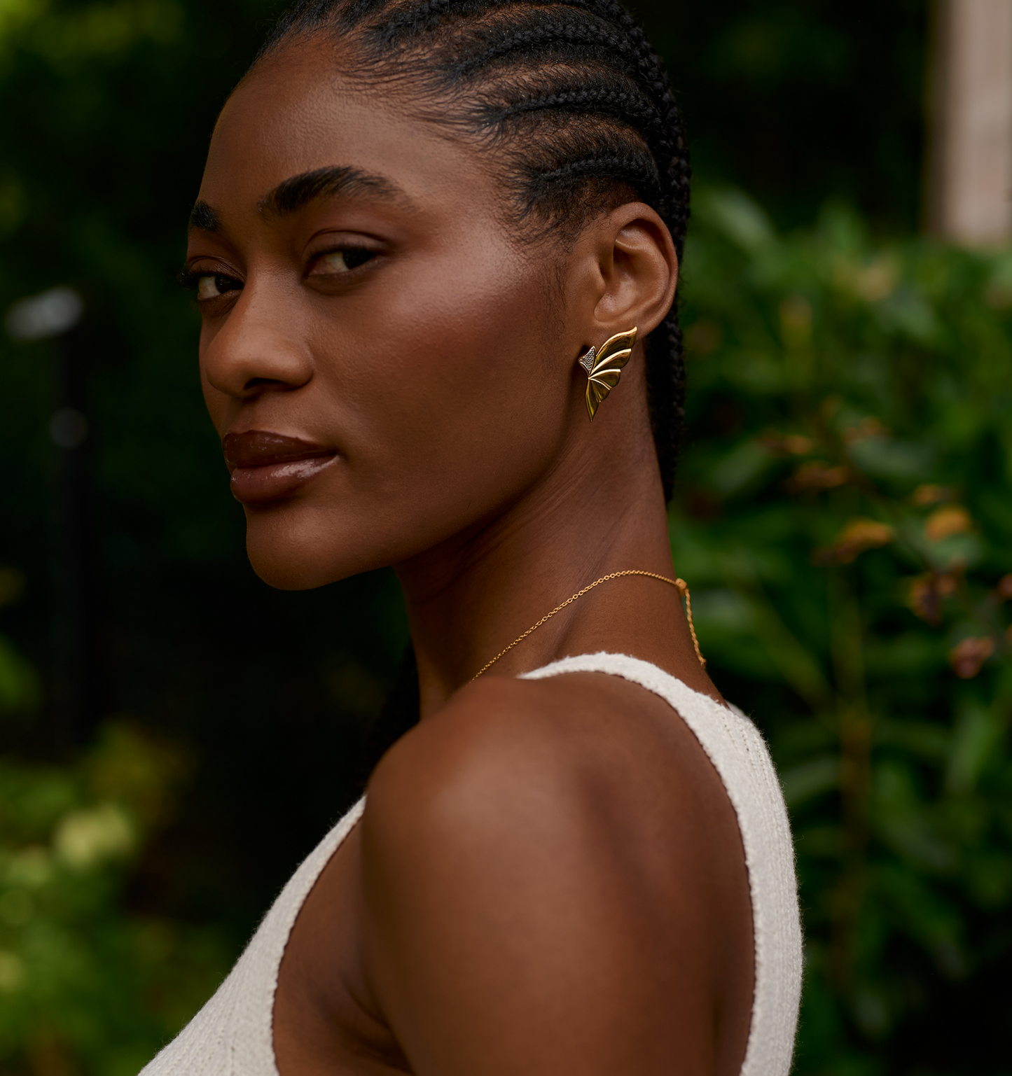 Close-up of a woman wearing layered gold Elara earrings inspired by butterfly wings.