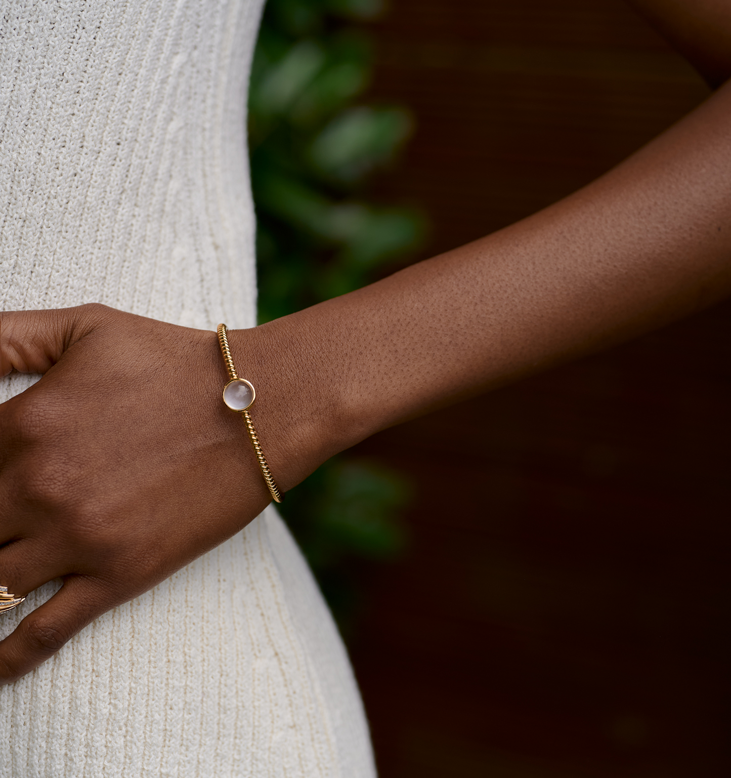 Close-up of a wrist wearing the Tarini Cuff, a gold bracelet with a round moonstone, symbolizing balance and intuition.