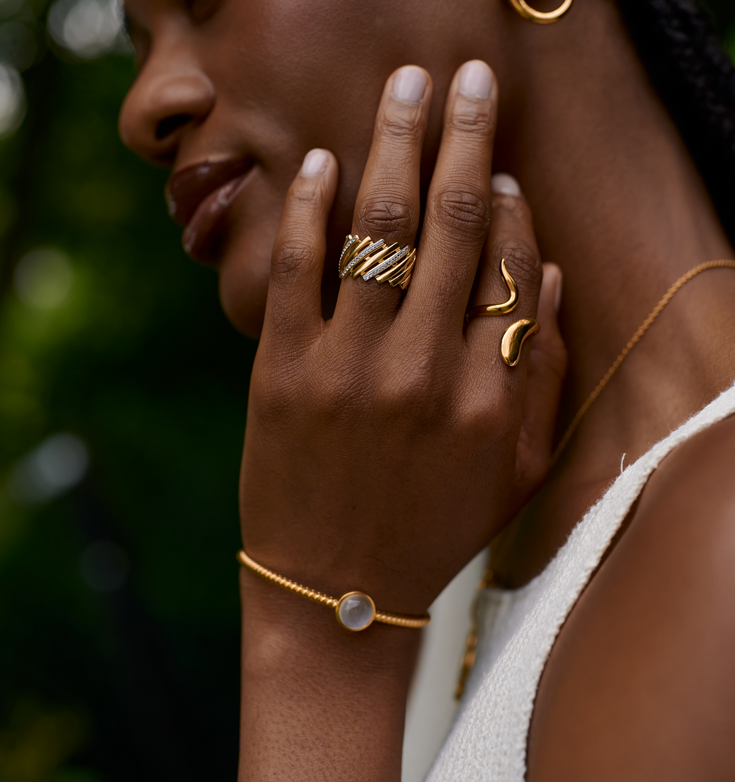 Close-up of a hand wearing a luminous gold Saachi Ring with elegant sweeping design