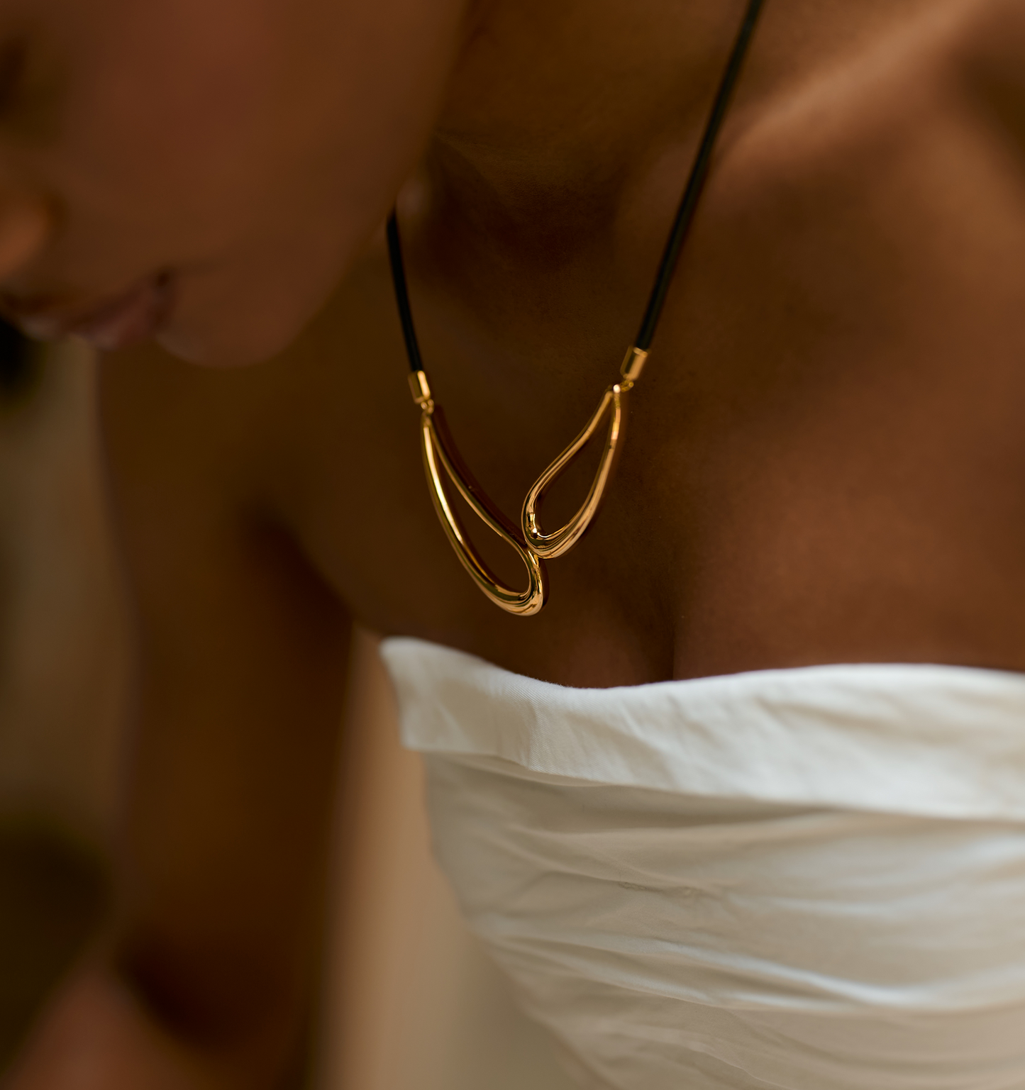 Saha Necklace twin sculpted gold forms on black cord worn on chest