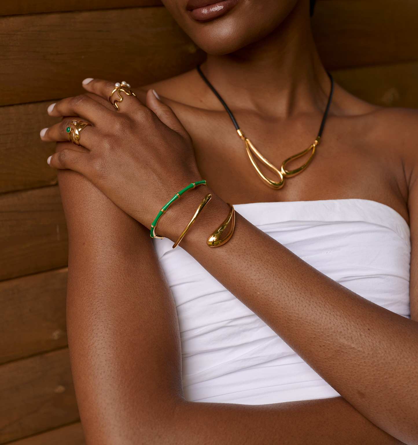 Baana Cuff green enamel and gold bamboo-inspired bracelet on woman's arm with matching gold jewelry