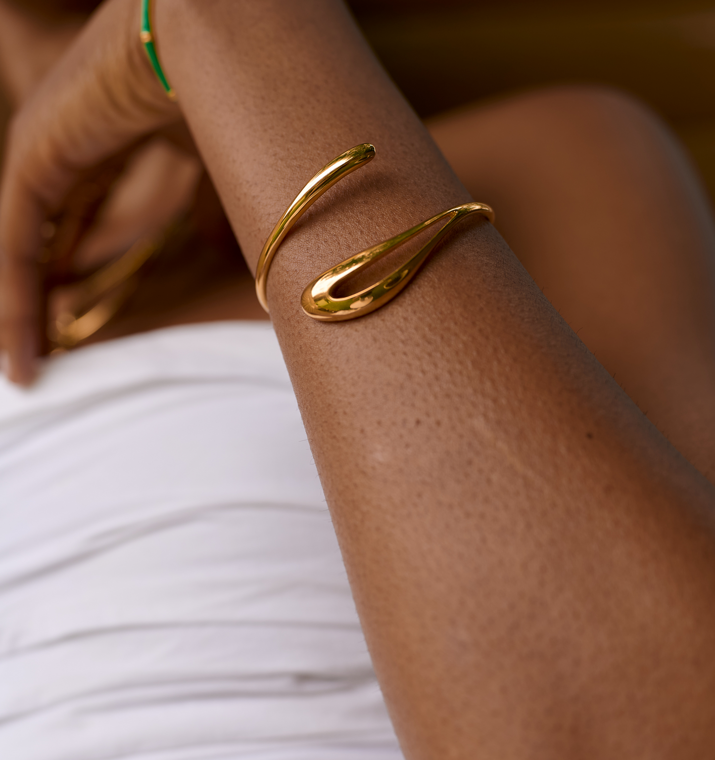 Close-up of a gold Oriya Cuff spiraled elegantly on a person's arm