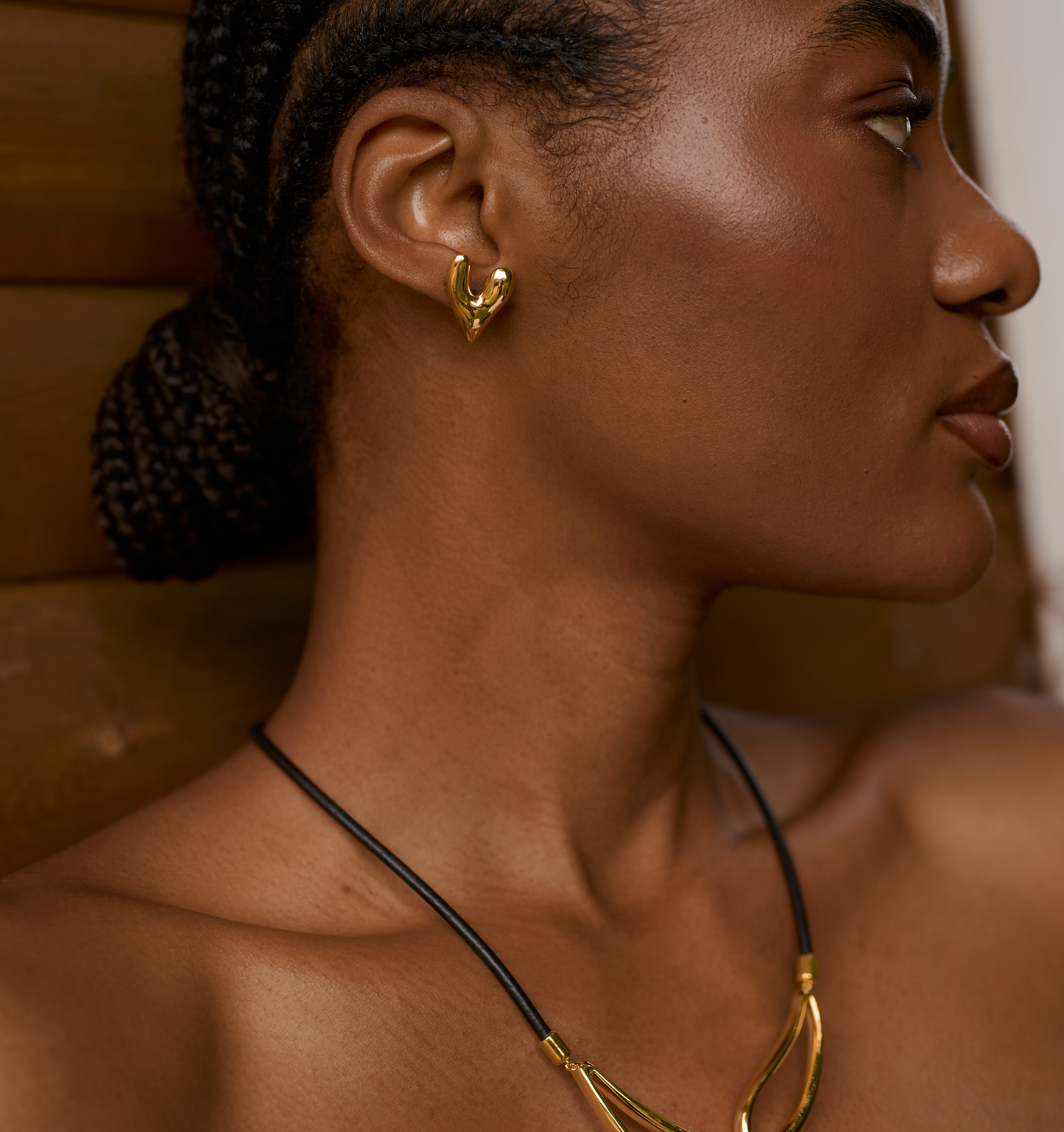 Close-up of model wearing gold-toned Avara Earrings with sculptural heart shape and organic finish