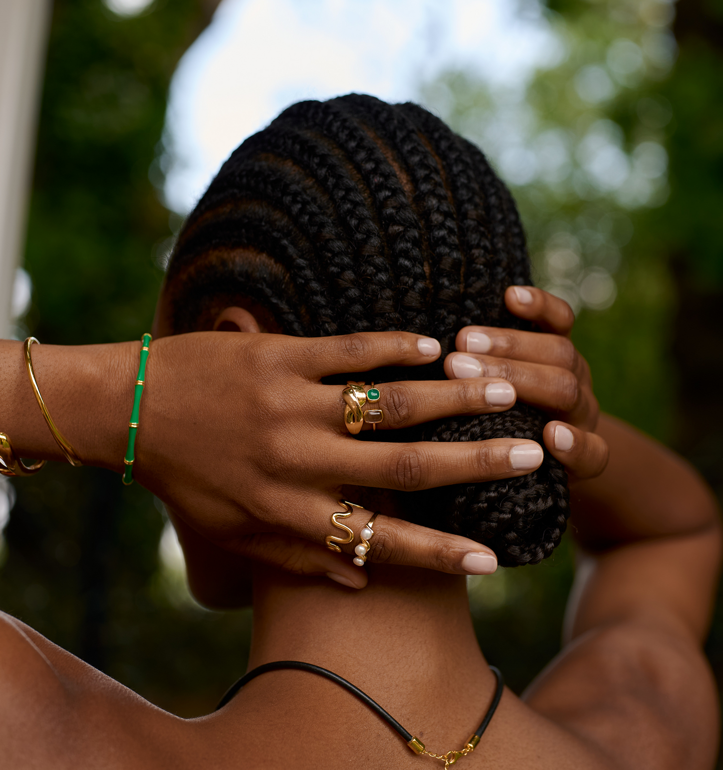 Close-up of hands with Niva Ring gold jewelry on fingers against natural background