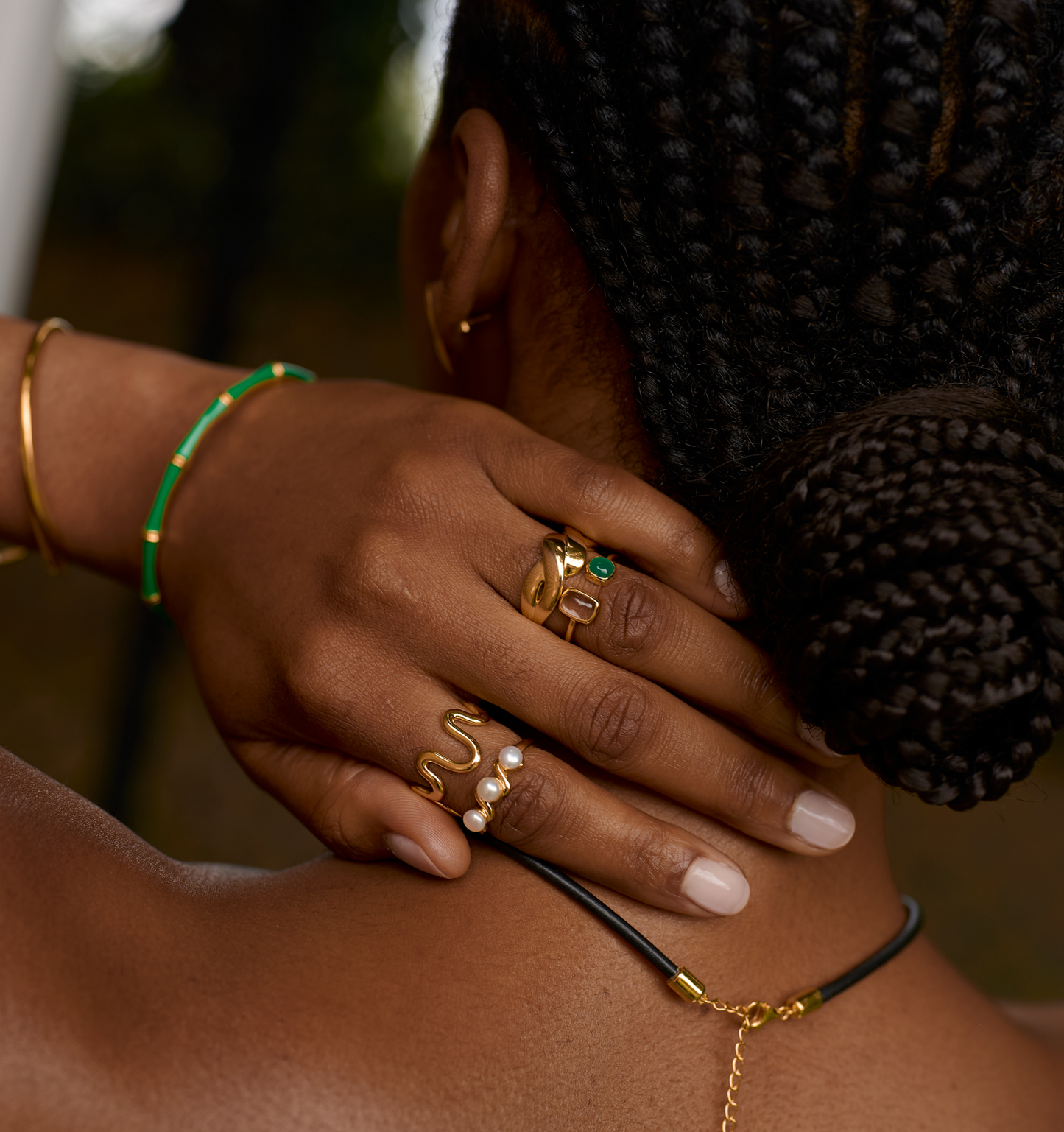Close-up of hand wearing Neer Ring with pearl and gold ripple design, showcasing elegant curved gold jewelry.