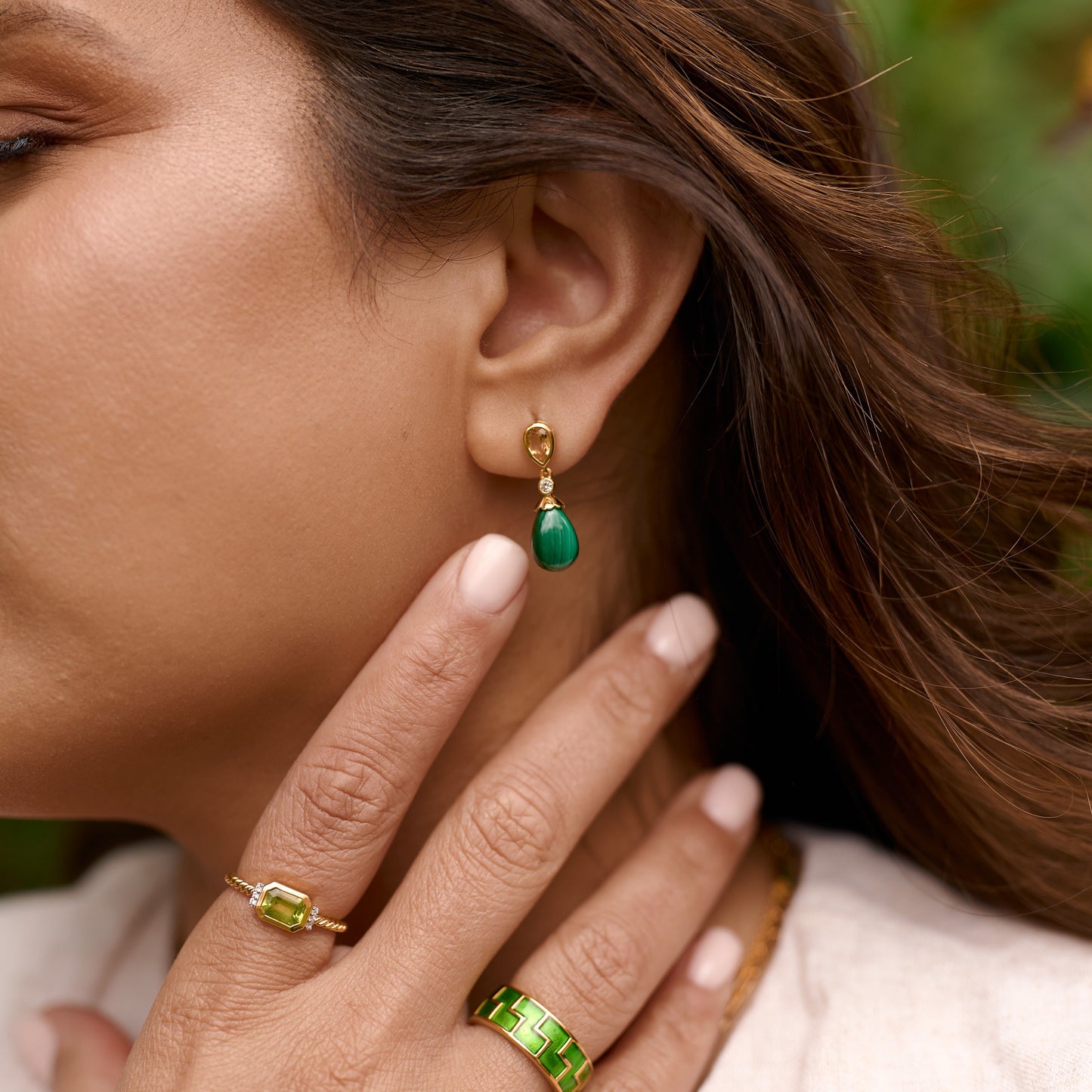 Close-up of a woman wearing Triya Earrings with green malachite drop and gold details, symbolizing calm and strength