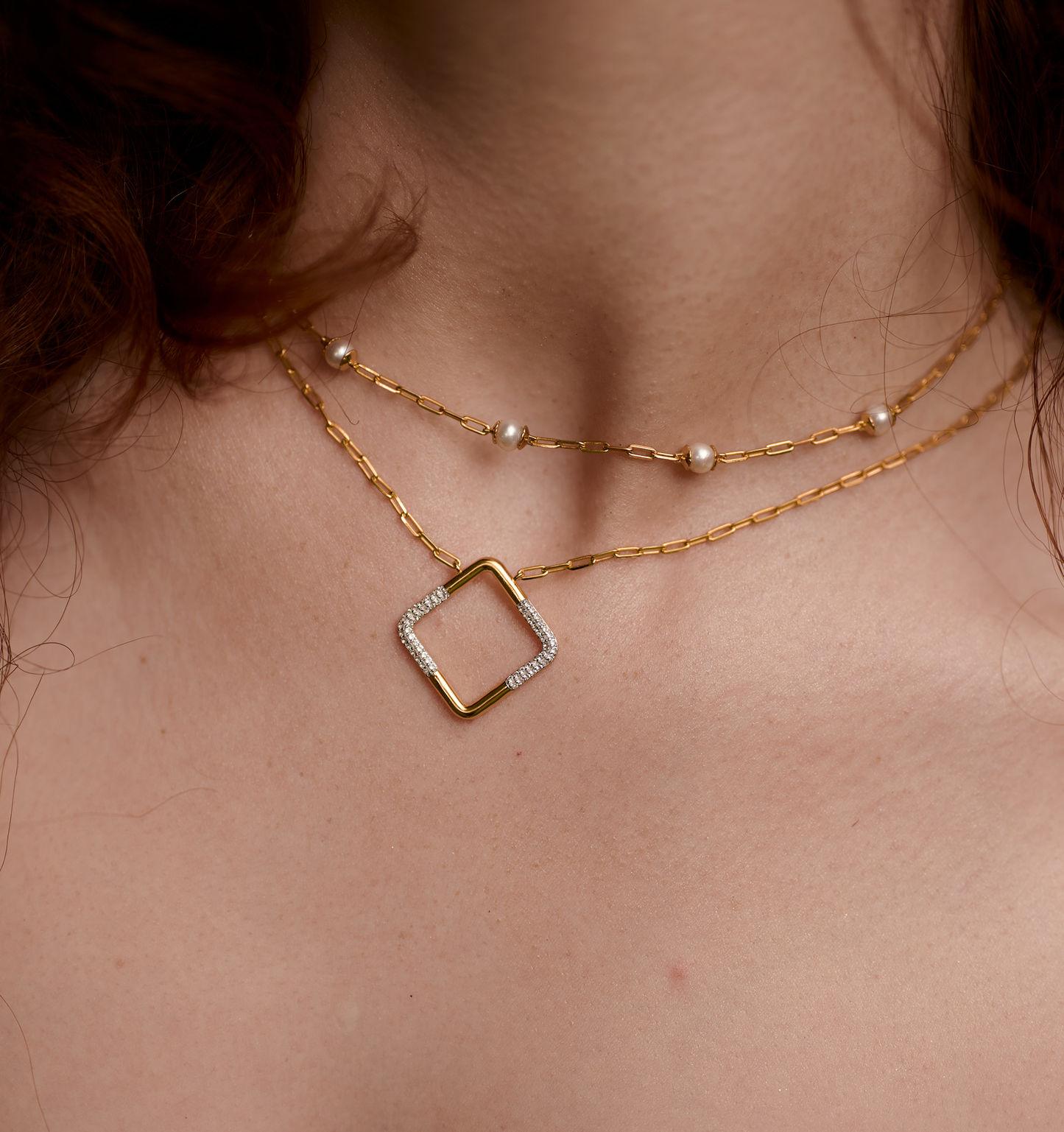 Close-up of Laya Necklace with gold chain, pearls, and square pendant on model's neck