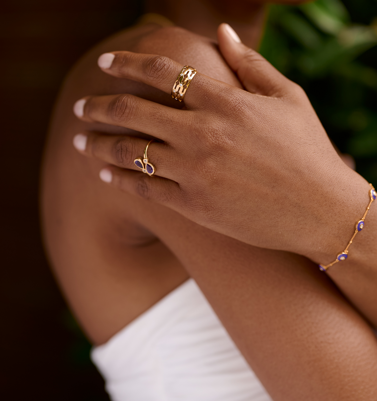 Close-up of a hand wearing a gold Svar Ring with seven lab-grown diamonds, paired with a delicate gold bracelet and ring.