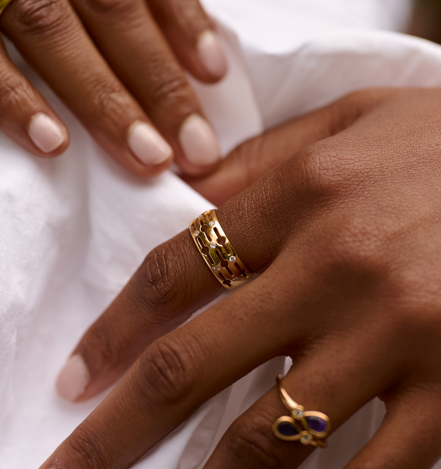 Close-up of a hand wearing a gold Svar Ring with intricate design and diamonds on the finger.
