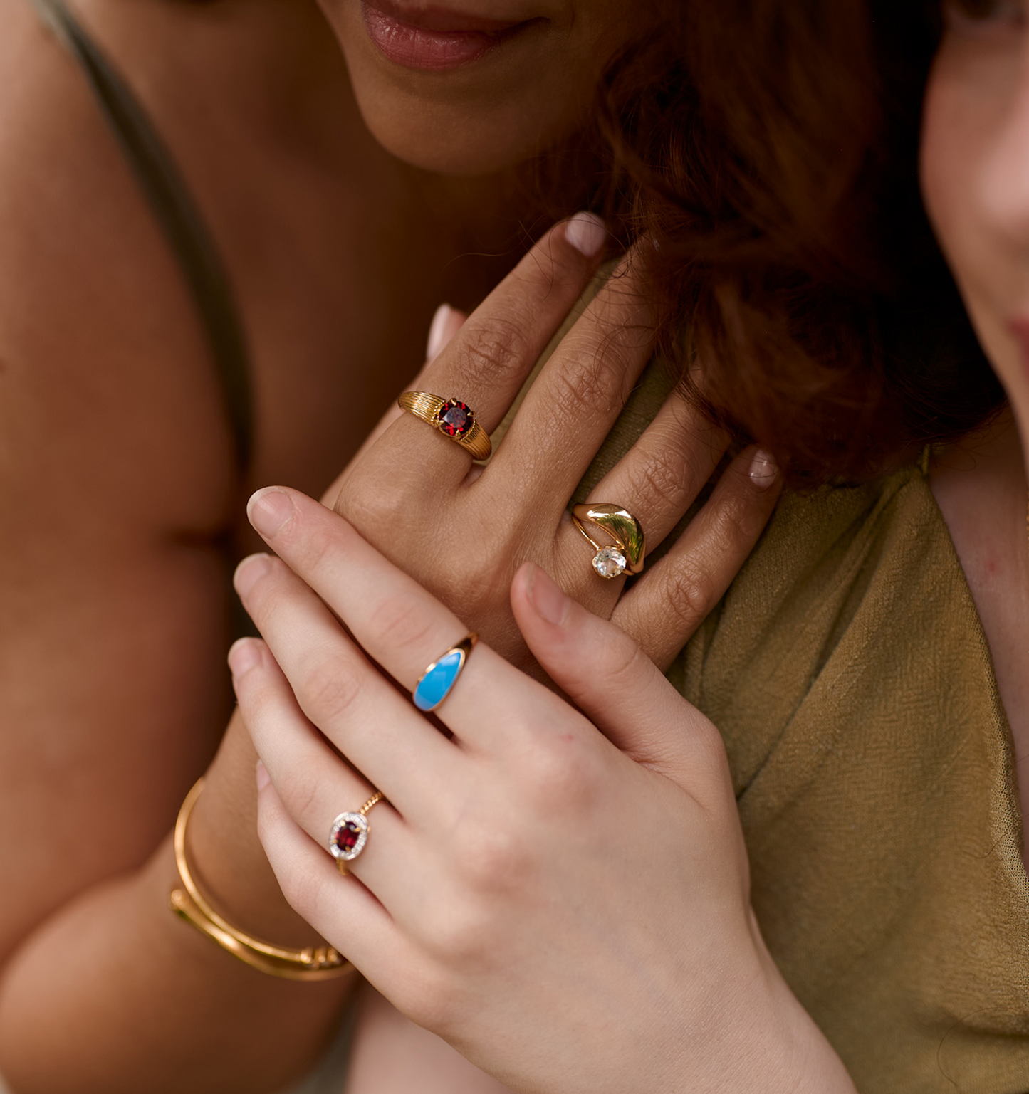 Close-up of hands wearing gold Alav Rings with colorful gemstones showcasing calm and harmonious design.
