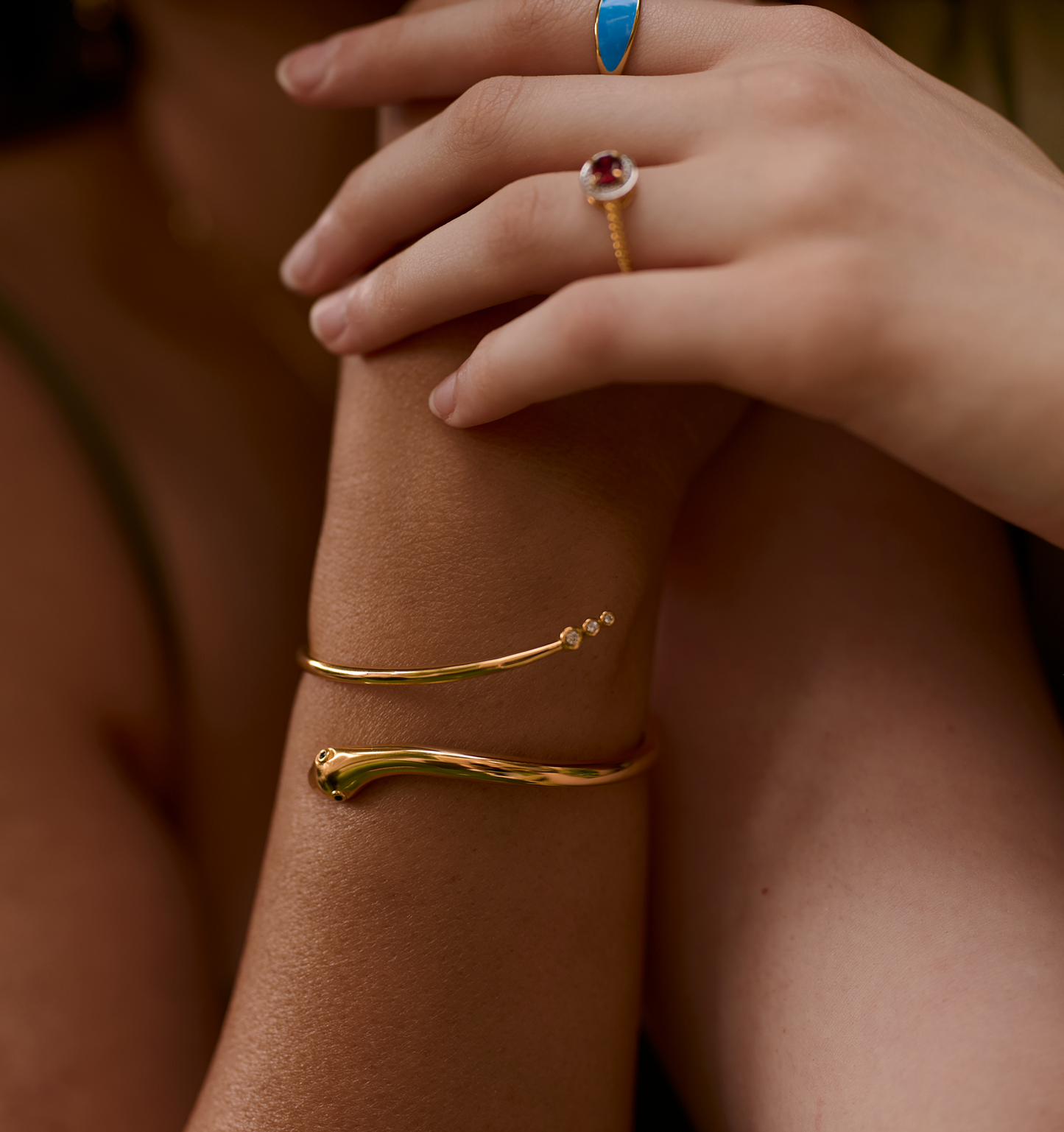 Golden sculptural serpent Sarpa Cuff bracelet with black spinel eyes and diamond accents on model's wrist