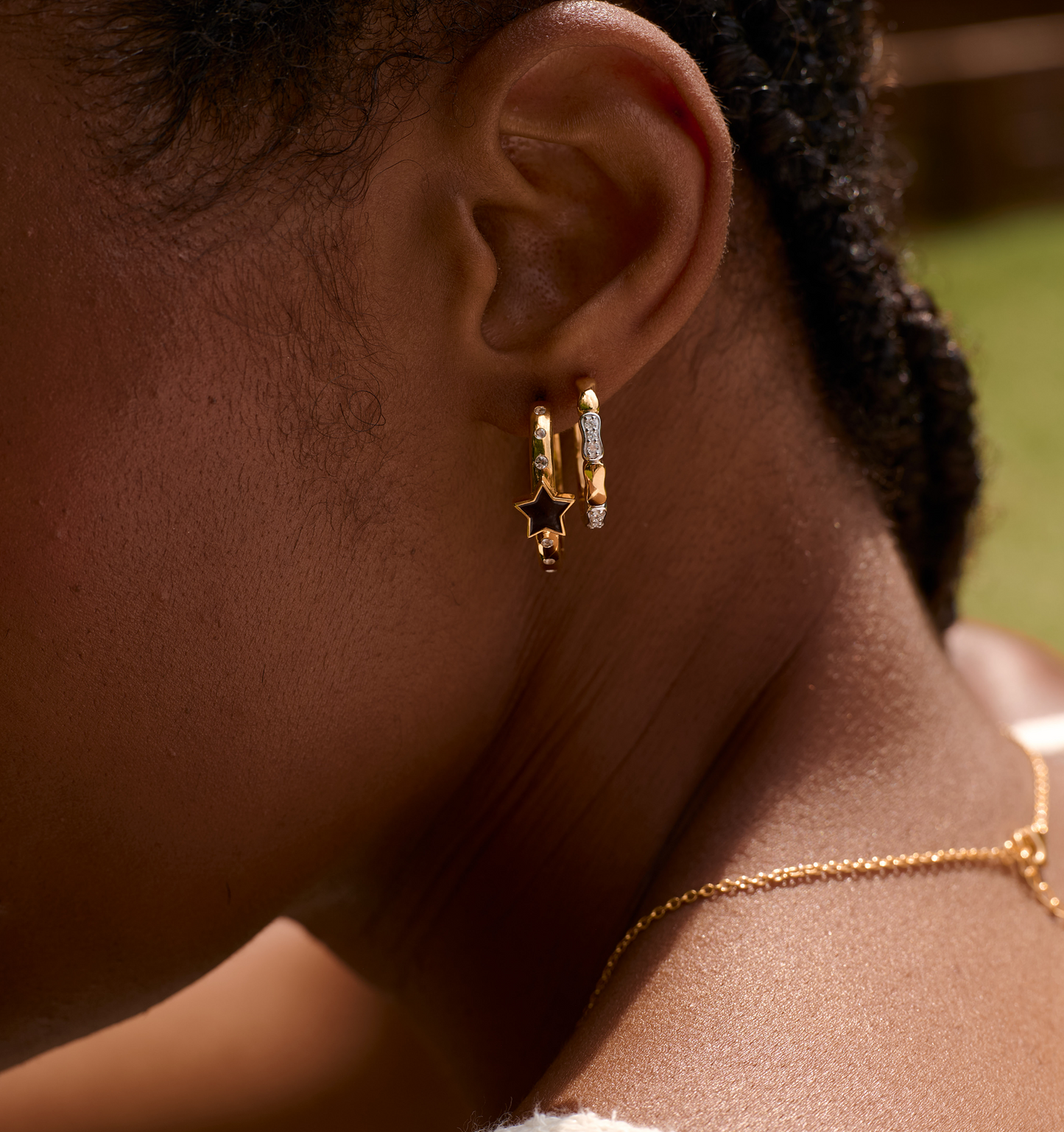 Close-up of ear wearing Orita Earrings with gold and silver tones and star charm design