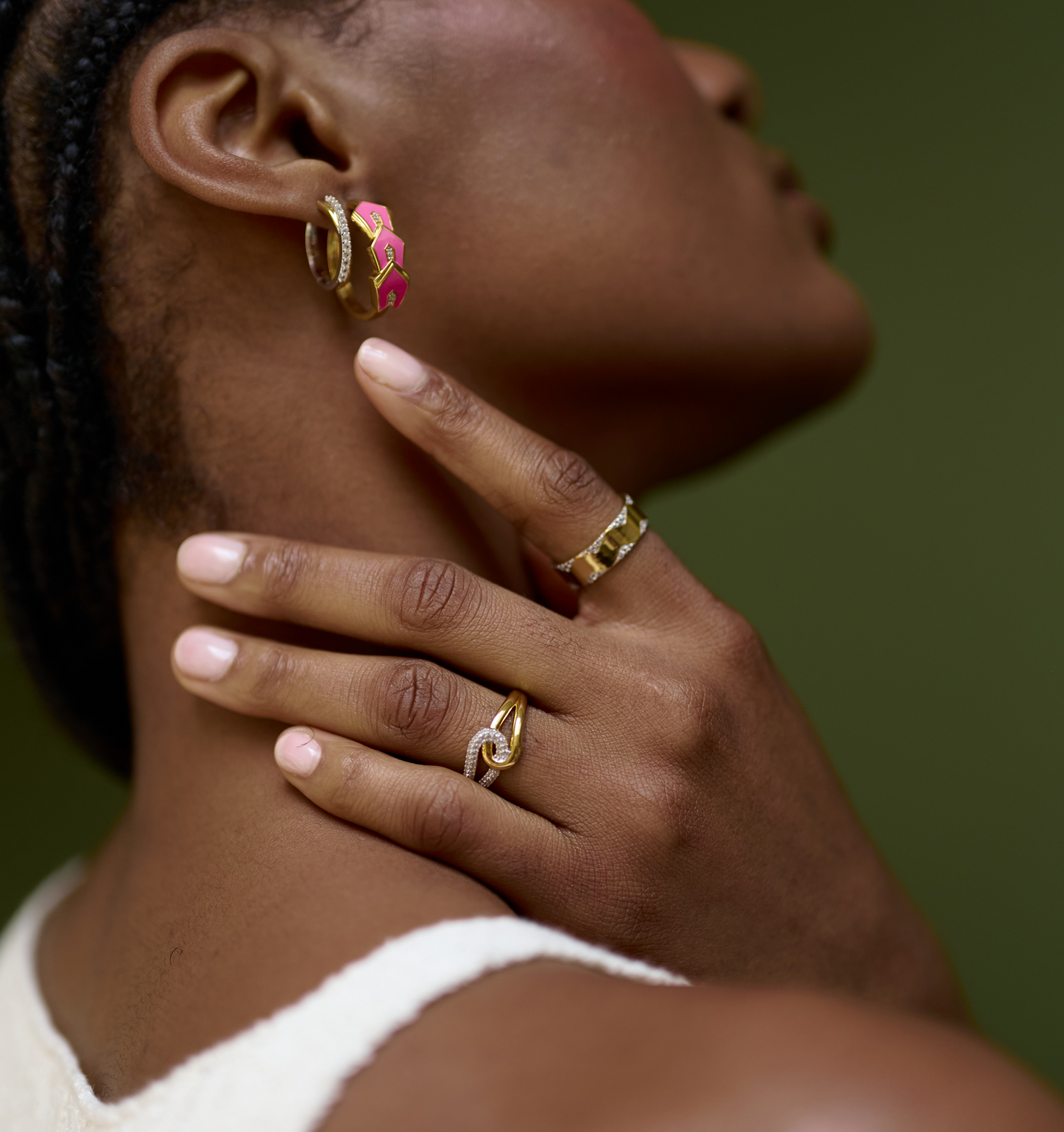 Close-up of woman wearing Sahaya Ring with gold and white topazes on finger against green background