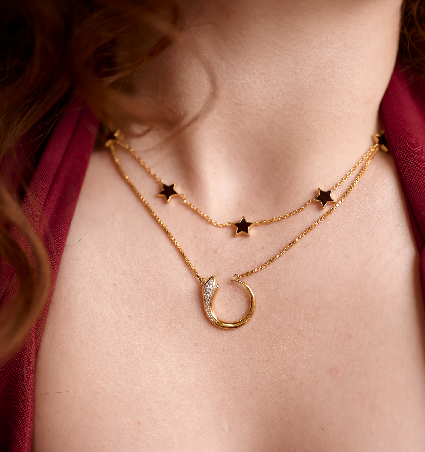 Close-up of Oroha Necklace featuring a gold serpent pendant with white topaz and a star chain detail on a woman's neck