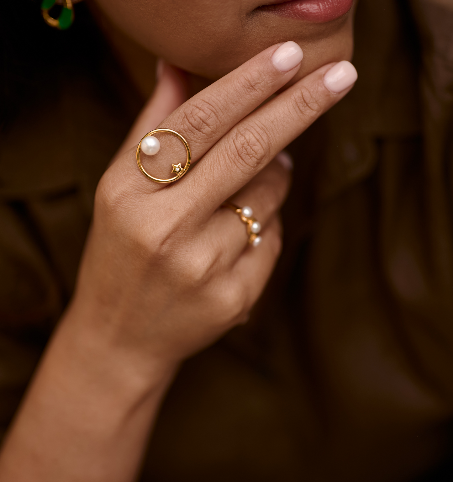 Close-up of a hand wearing an Amishti Ring with a pearl and star design in gold.