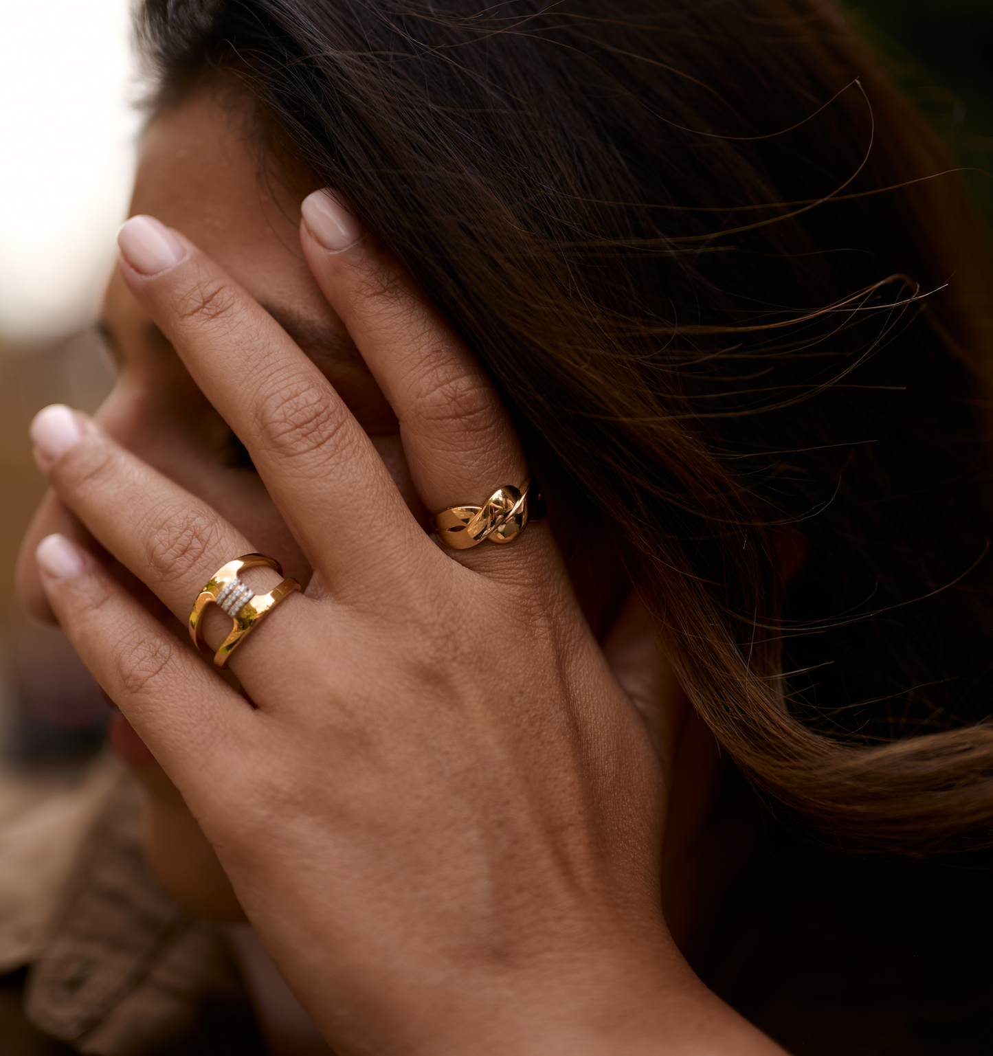 Close-up of a hand wearing two gold Niva Rings symbolizing fluid and eternal presence