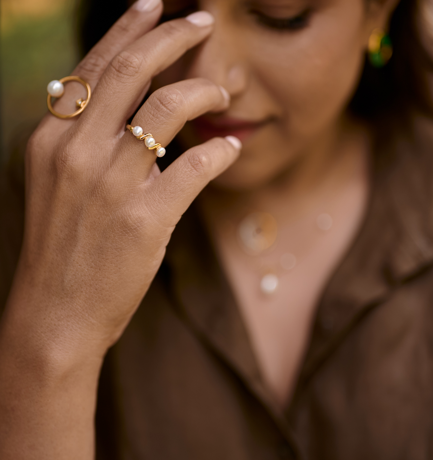 Close-up of a hand wearing the Tirya Ring with three pearls on a gold band, showcasing elegant feminine style.