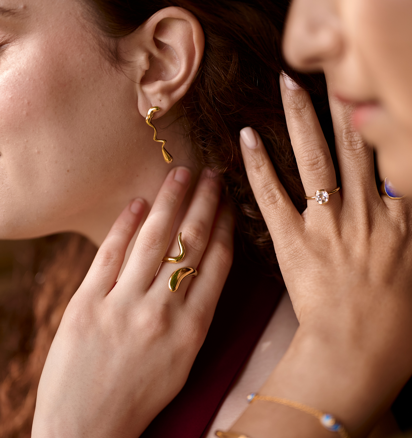 Close-up of a woman wearing fluid gold Caia Earrings with abstract gold rings and a delicate gold bracelet.