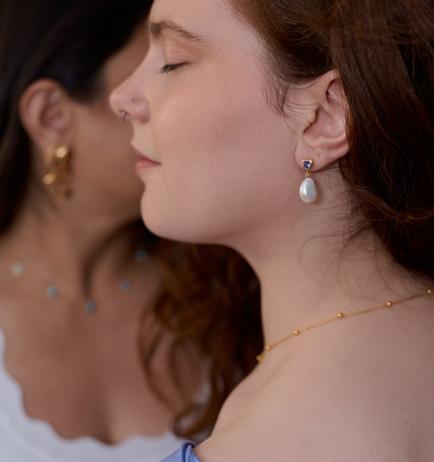 Close-up of a woman wearing Hridaya Earrings with tanzanite and pearl detail.