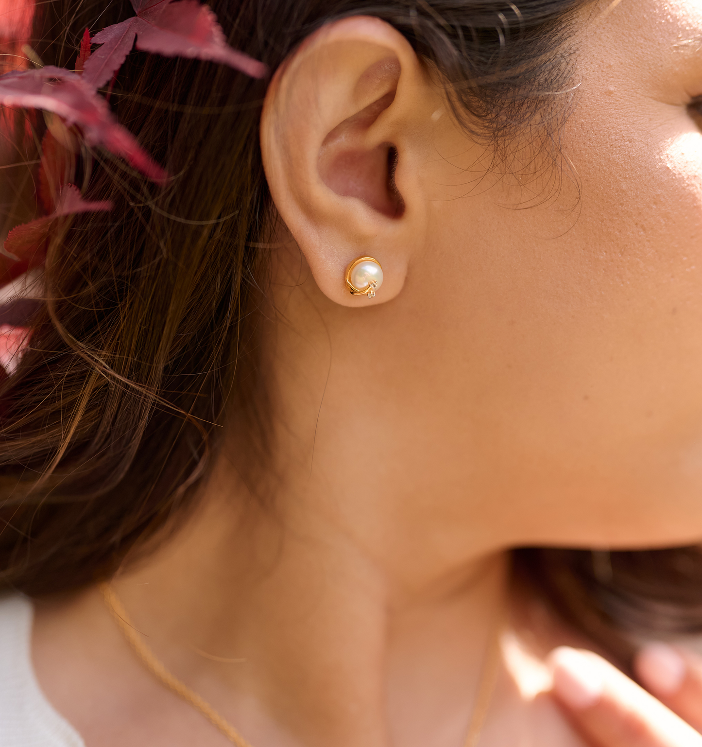 Close-up of ear wearing Poorna Earrings featuring a gold full moon and two angel stars design
