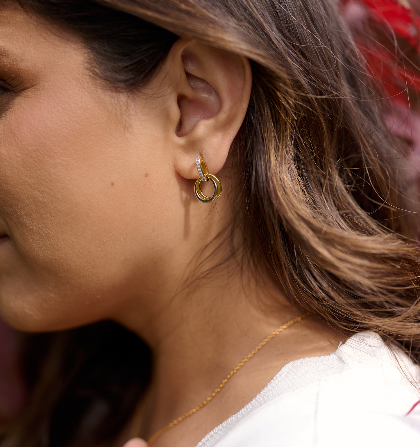 Close-up of a woman wearing elegant gold Nirya Earrings with intertwined circular design