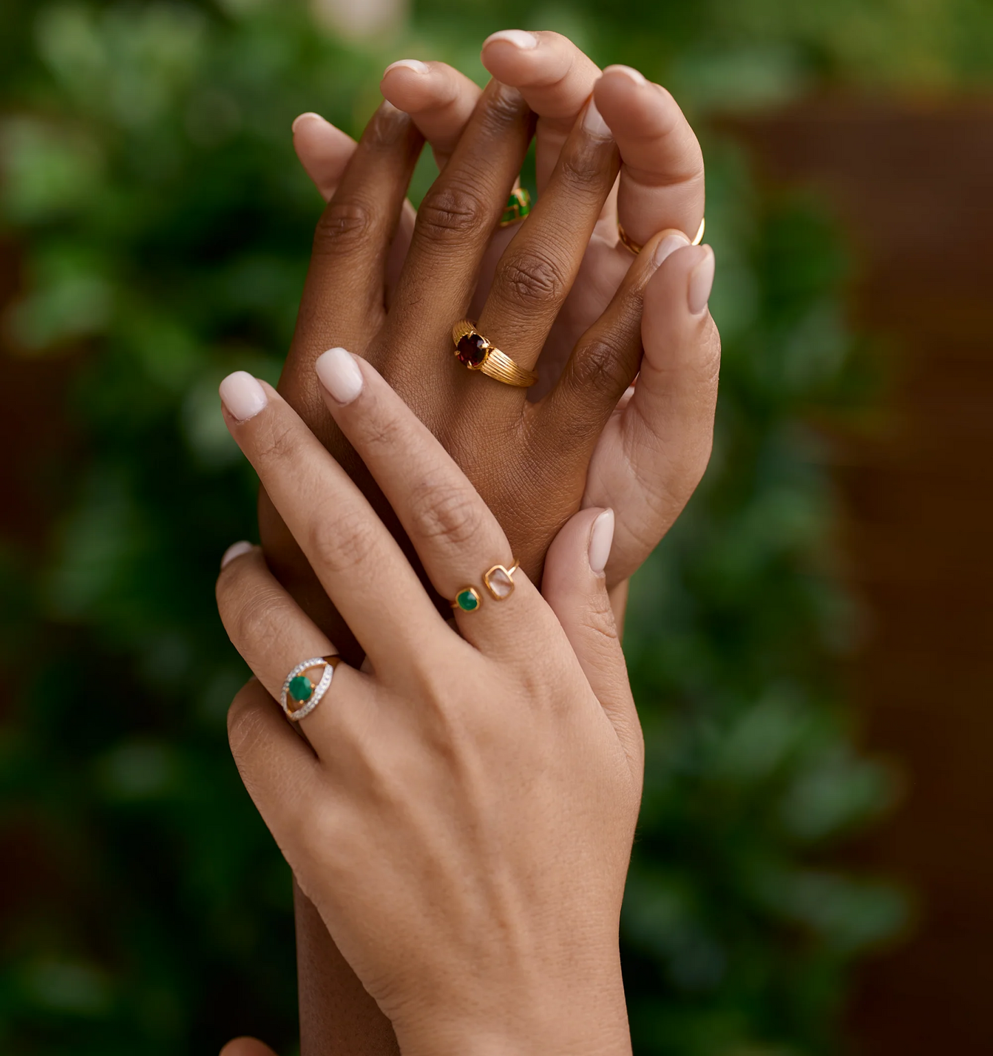 Close-up of hands wearing gold Ishaya Ring with deep red garnet gemstone