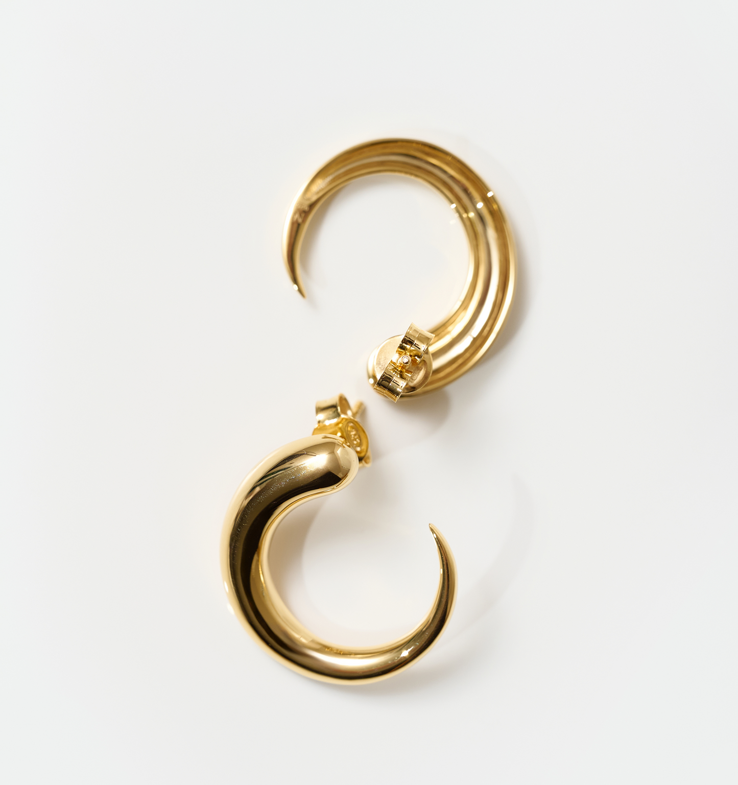 Gold sculptural hoop Sora earrings with modern minimalist design on white background