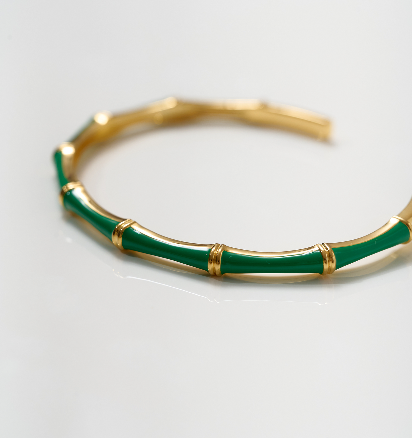 Baana Cuff gold bracelet with green enamel bamboo-inspired segments on white background
