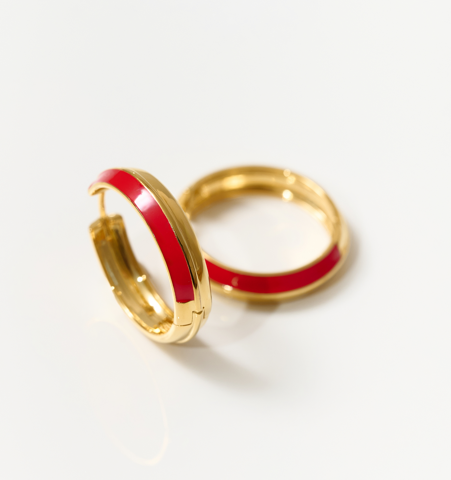 Gold hoop earrings with deep red enamel detailing called Rati Hoop, symbolizing feminine strength and elegance.