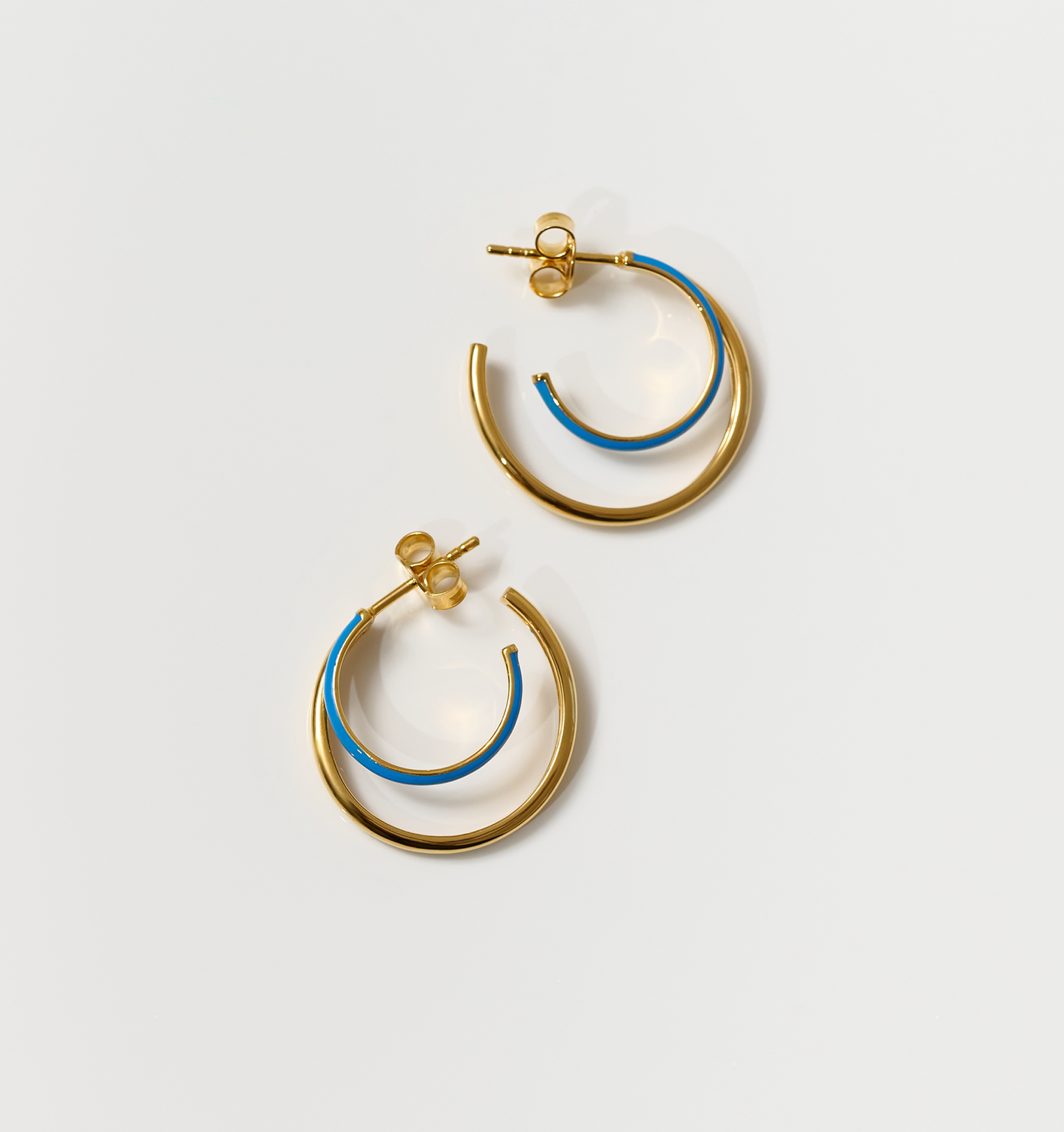 Pair of Soma Hoops with gold and turquoise enamel crescent design on white background