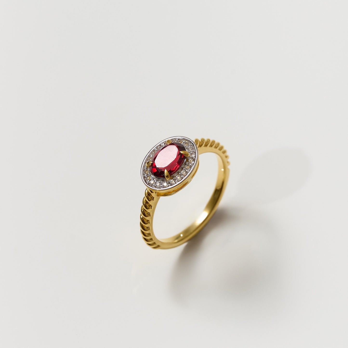 Agira Ring gold band with central garnet surrounded by white topaz halo