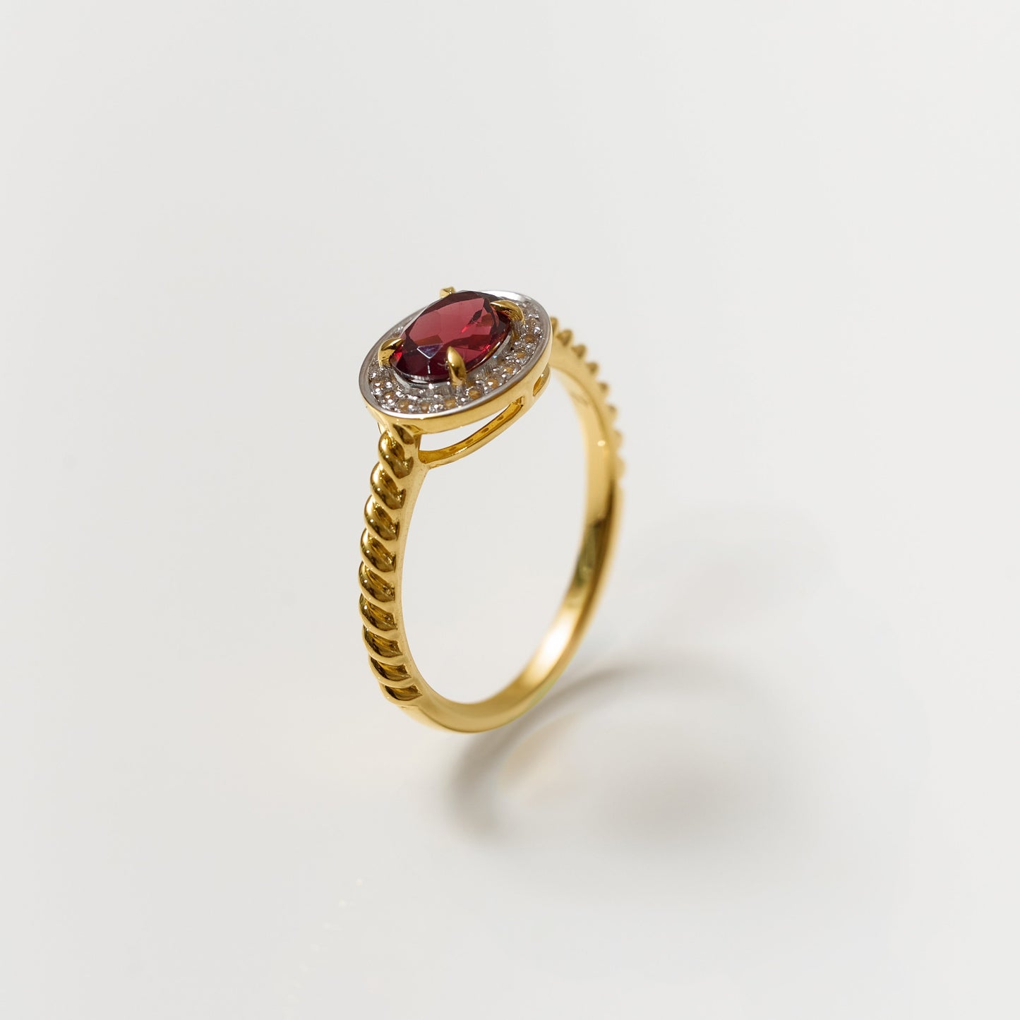 Agira Ring with garnet center and white topaz halo on gold twisted band