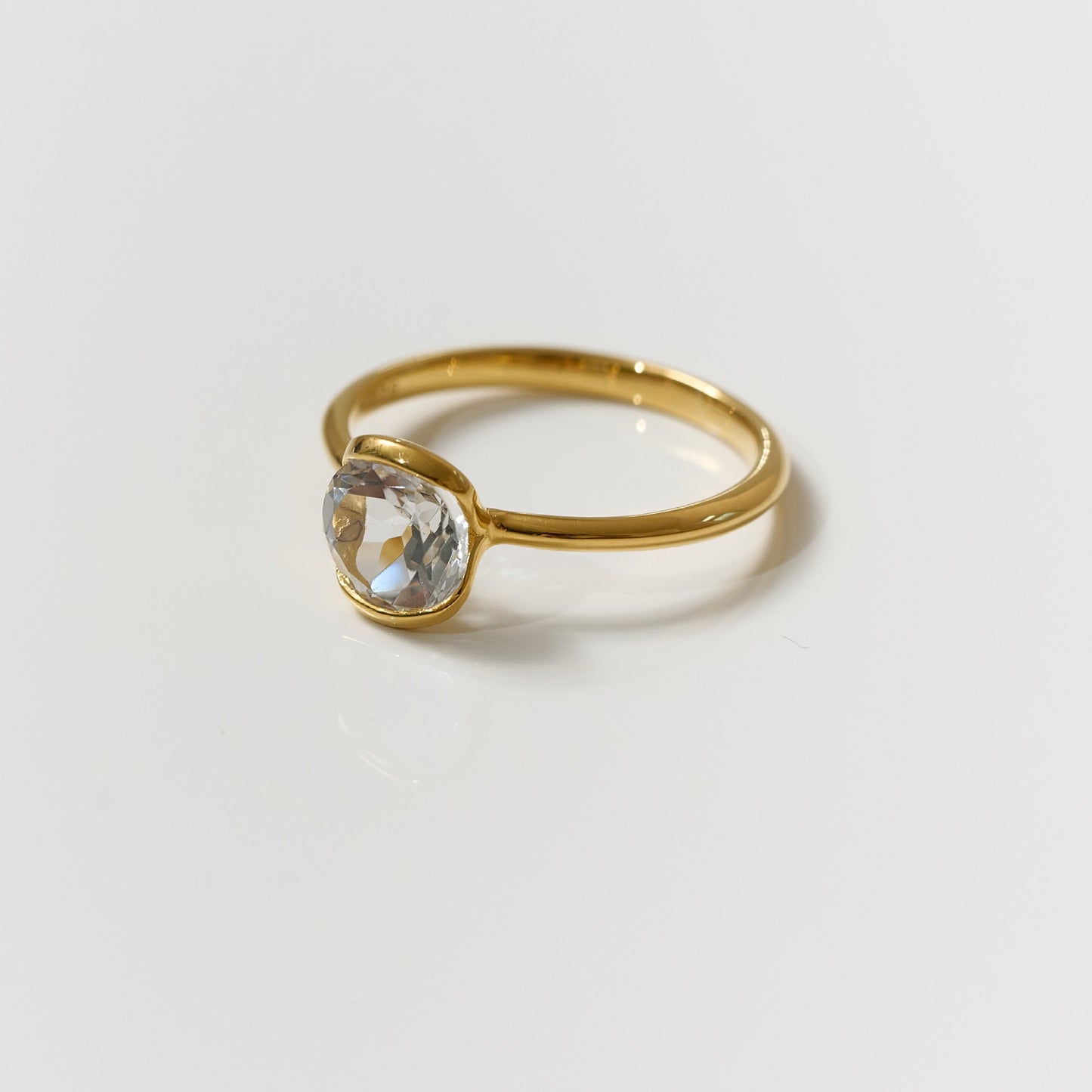 Ruhi Ring featuring a delicate white topaz set in a polished gold band reflecting clarity and elegance