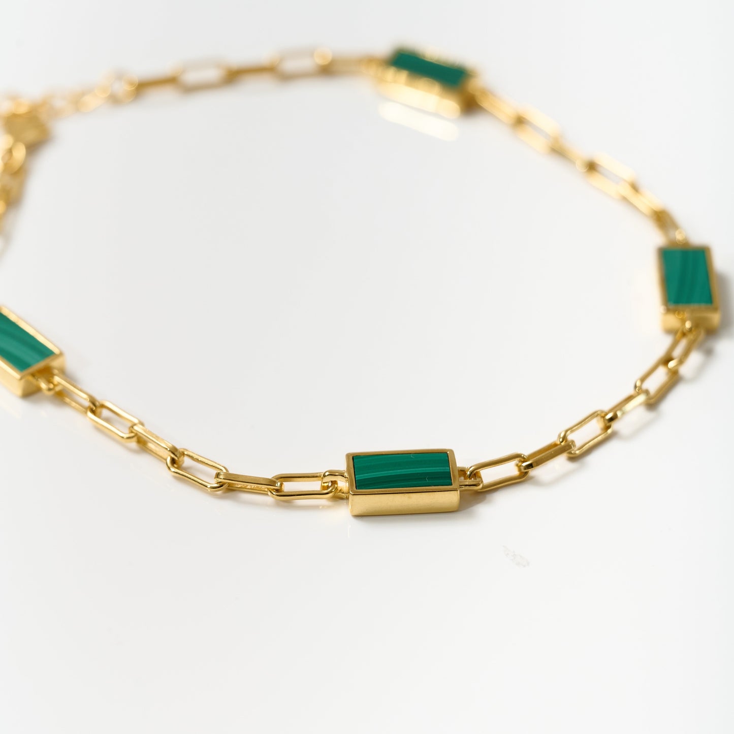 Gold Mann Bracelet with green rectangular stones and chain links on white background
