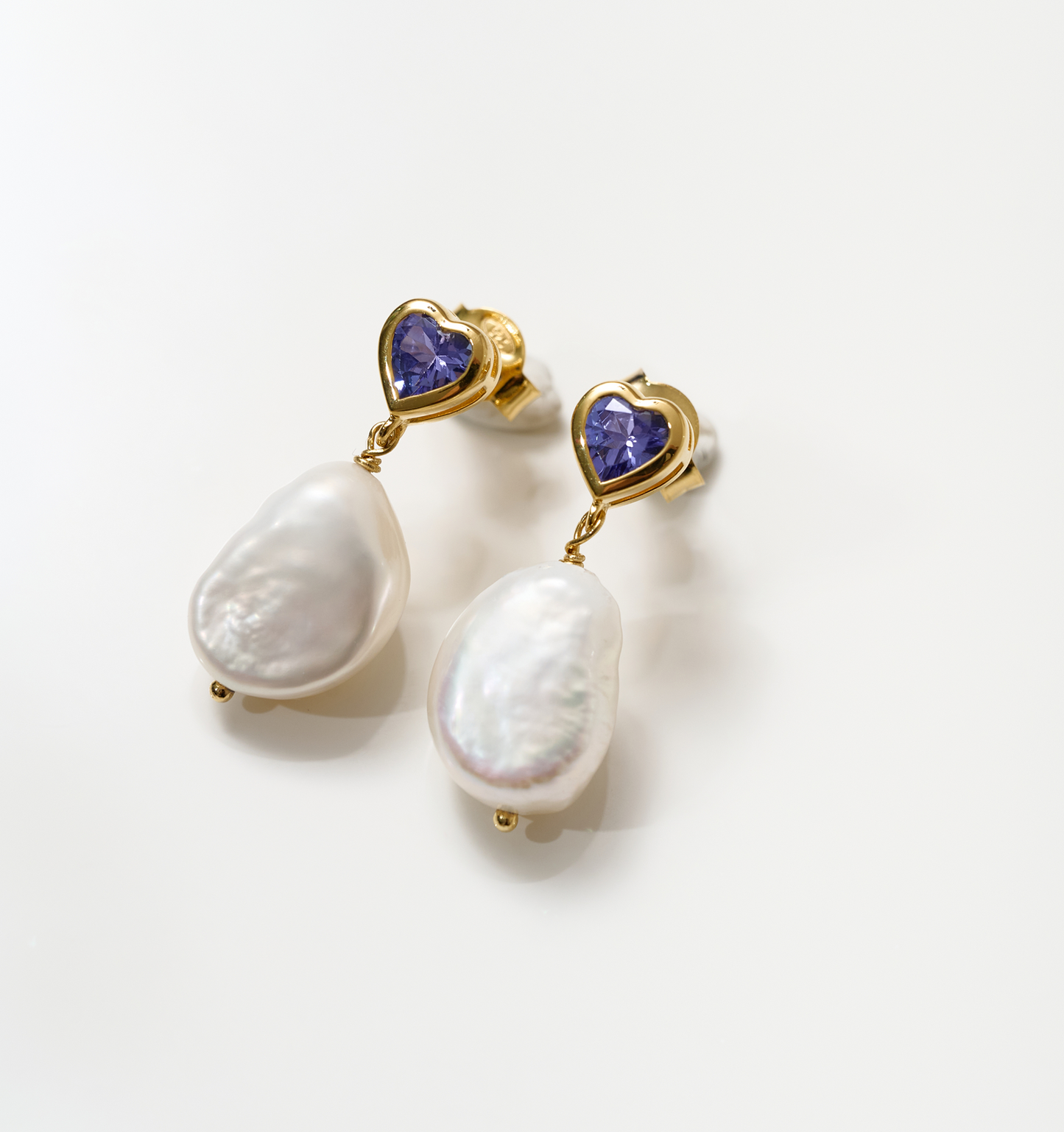 Hridaya Earrings with heart-shaped tanzanite and dangling white pearls in gold setting