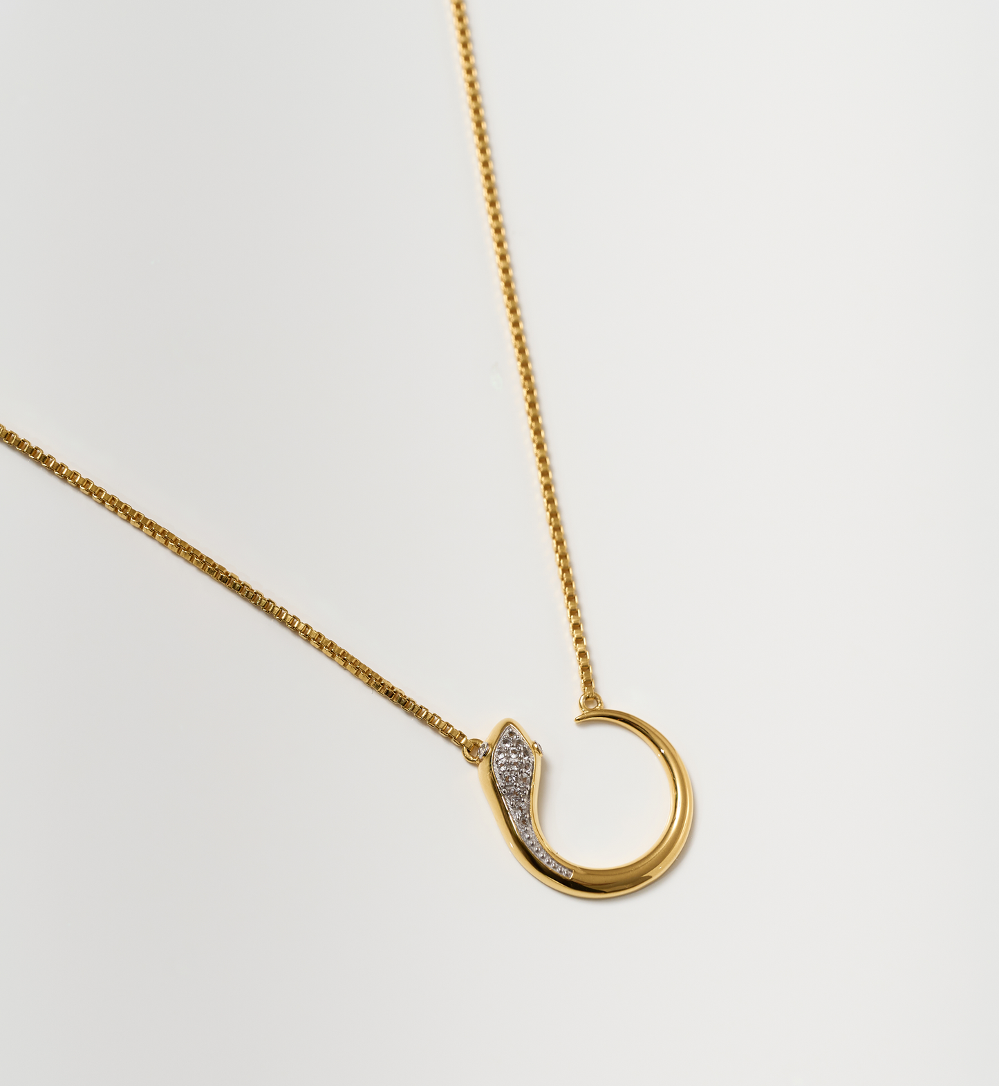 Oroha Necklace gold serpent pendant with white topaz on delicate chain against white background