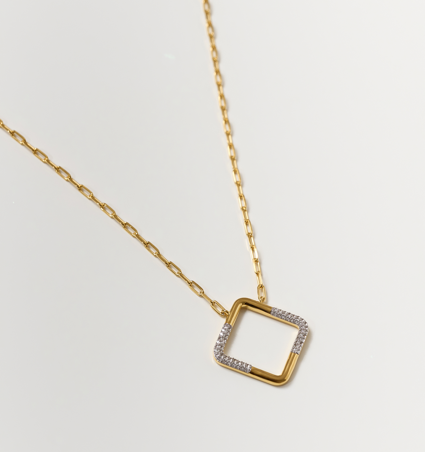 Trayi Necklace gold chain with square pendant partially encrusted with white topaz gemstones on white background