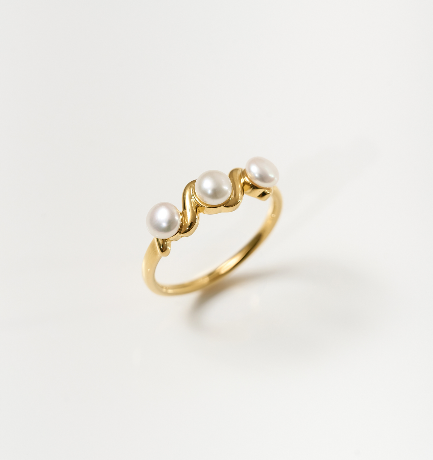 Tirya Ring with three pearls set on a golden wavy band symbolizing feminine elegance