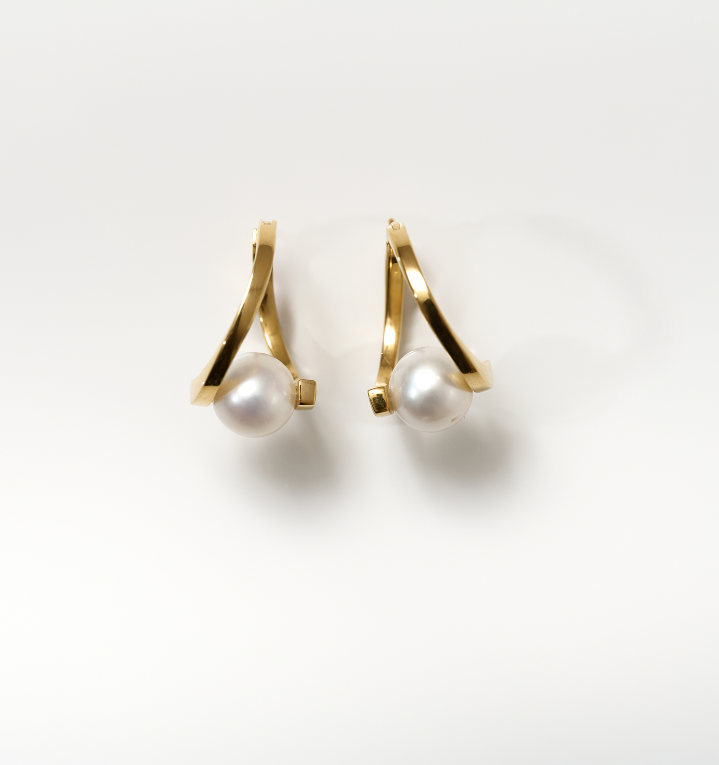 Gold Sharvani Earrings with horned curve design and single pearl accent on white background