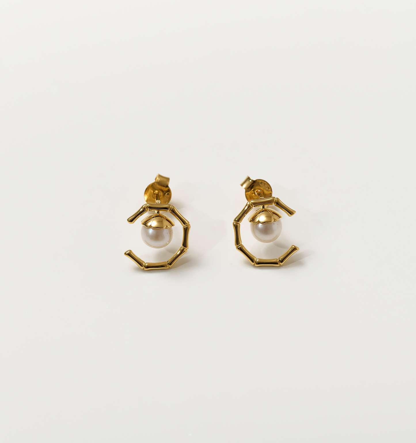 Kavach Earrings featuring gold bamboo-like segmented design with a single pearl centerpiece symbolizing resilient elegance and grace.