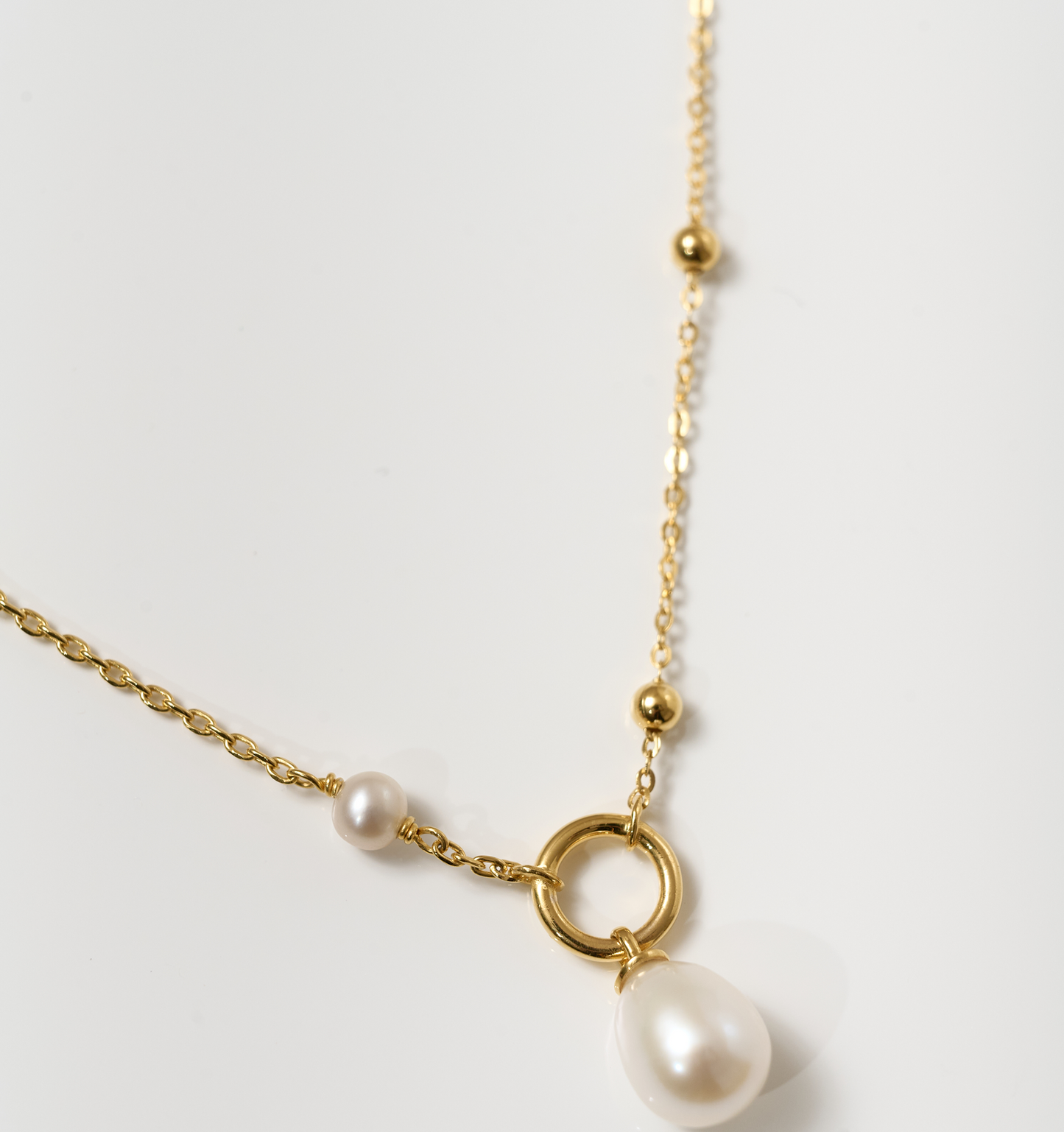 Argha Necklace featuring a gold chain with a circular pendant and descending pearl detail
