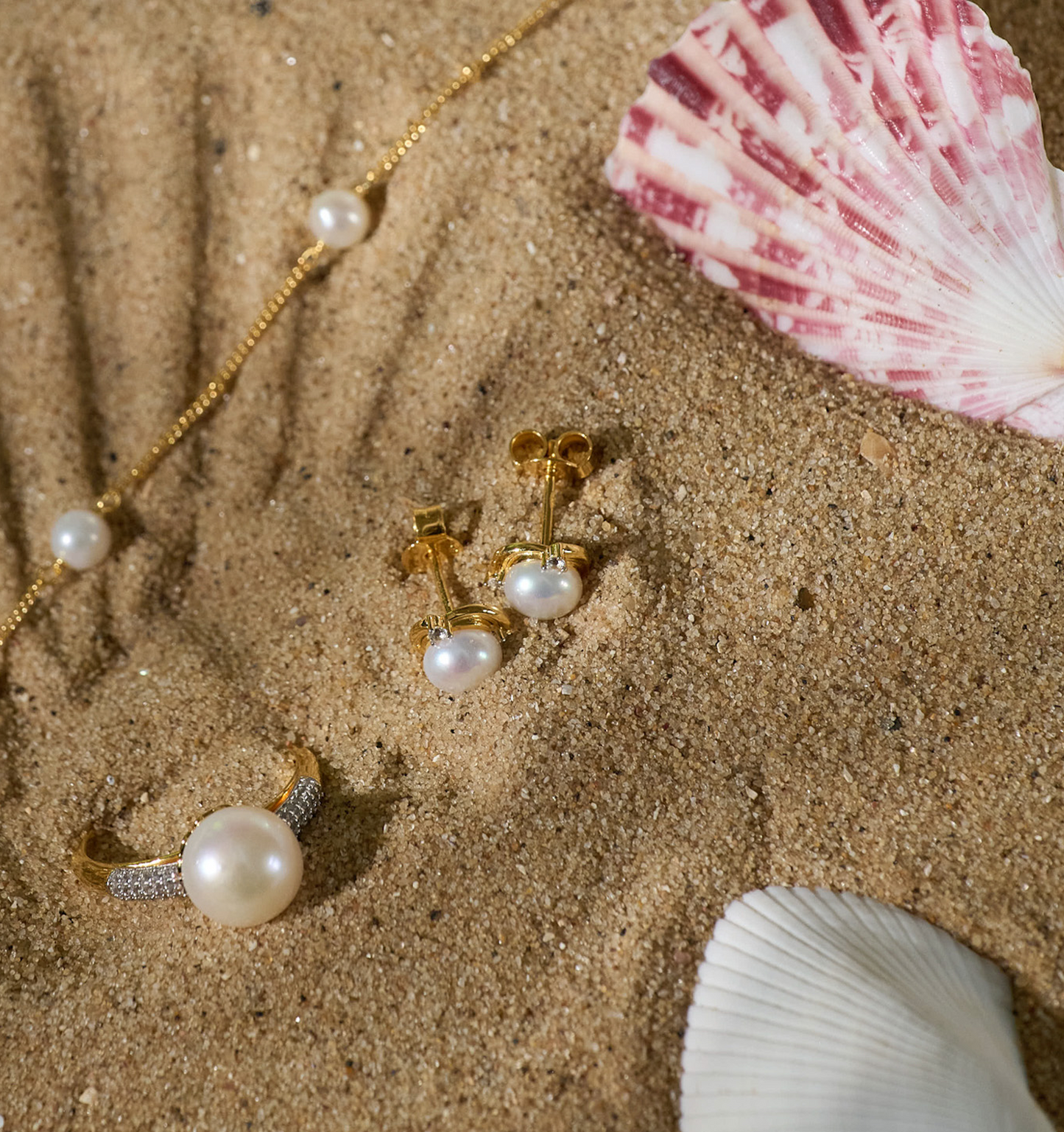 Nayana Earrings with pearls and gold studs on sand with seashells