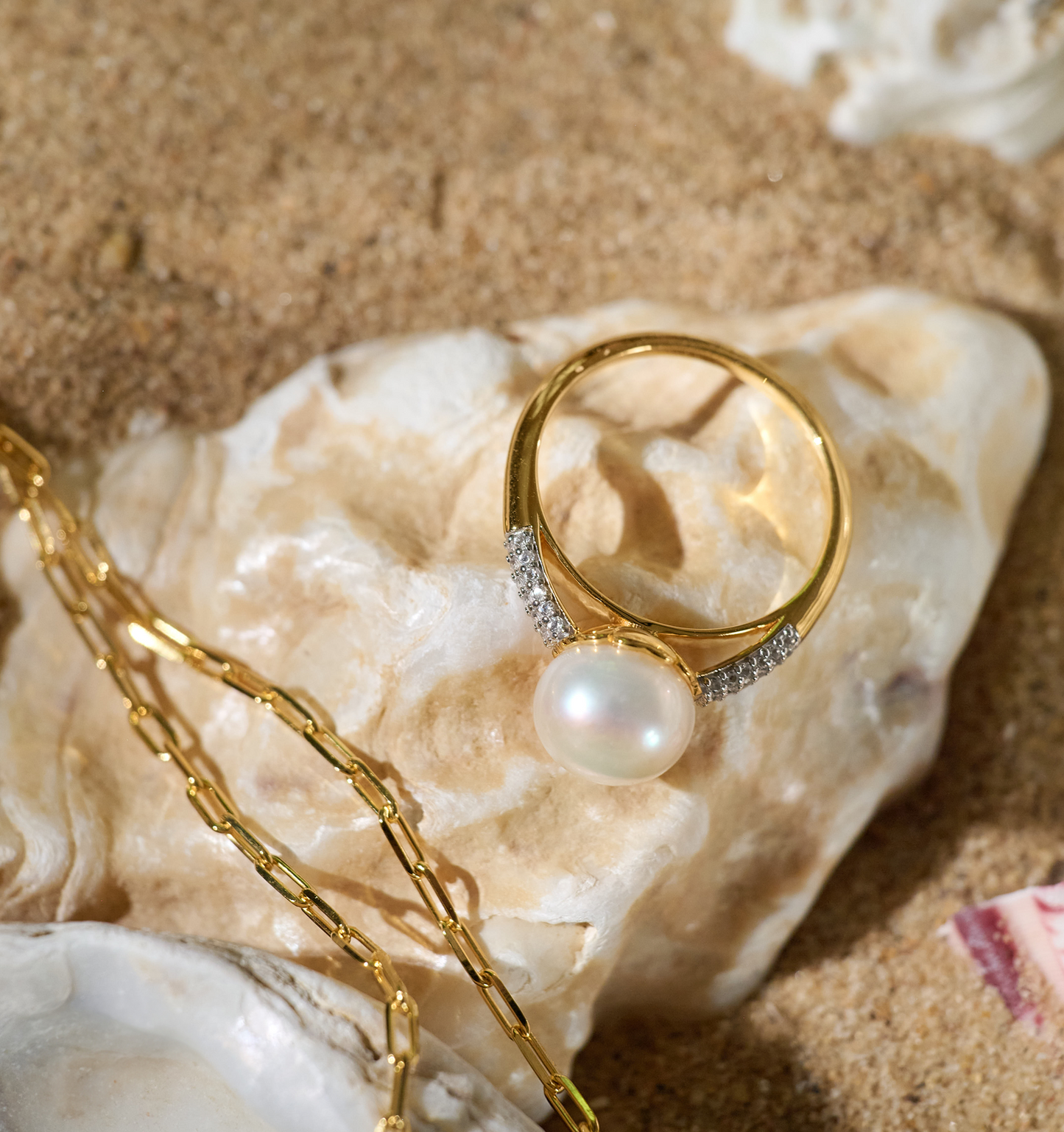 Sitara Ring gold with luminous pearl and halo of white topaz on shell and sand background