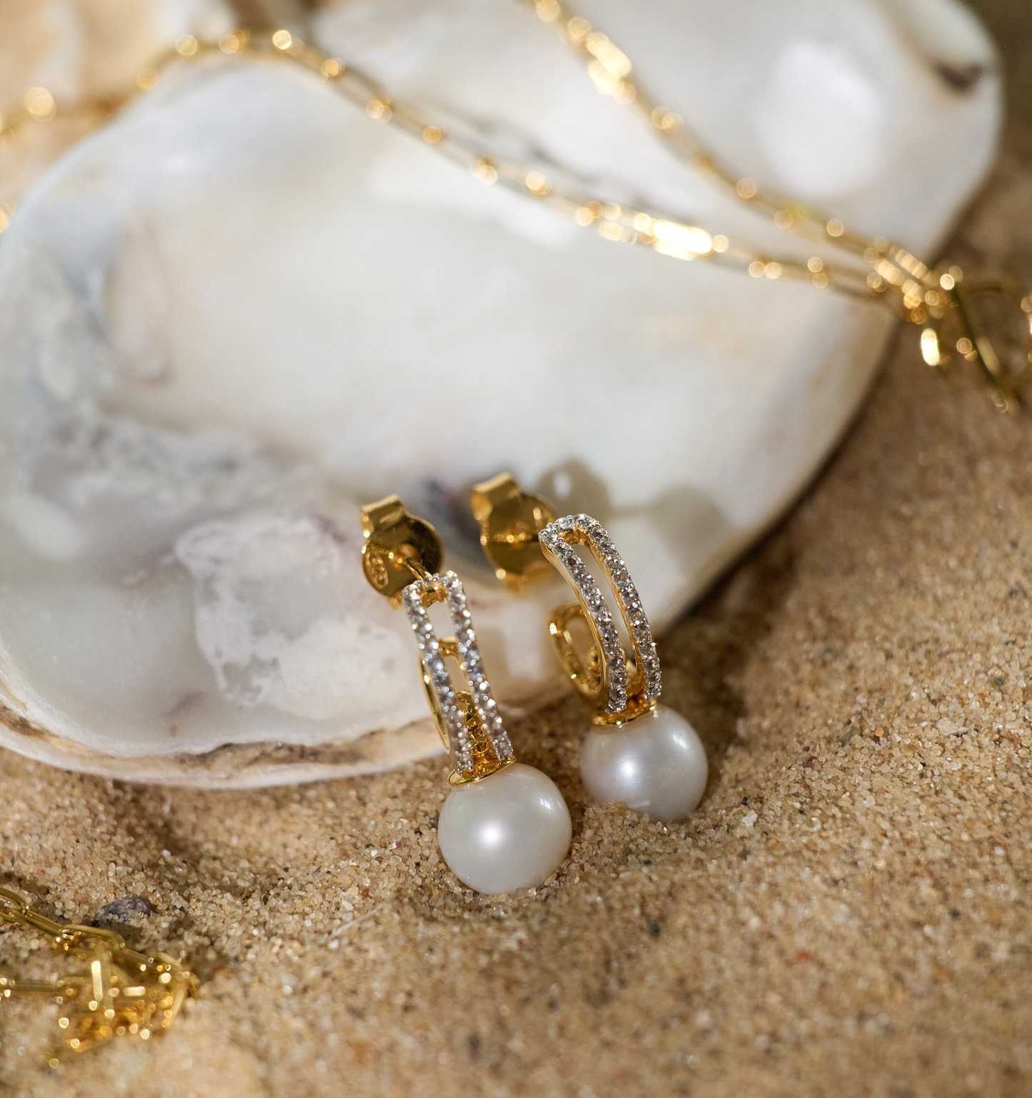 Gold Tarasa Earrings with pearls and diamond accents on sand and shell background