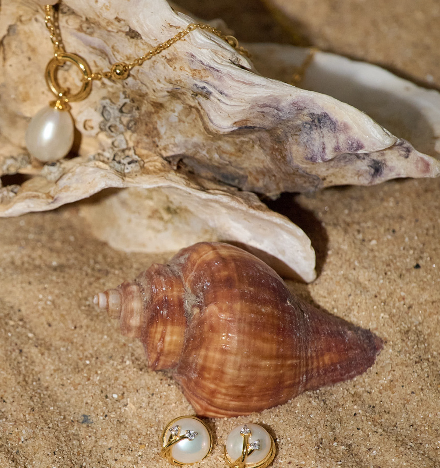 Poorna Earrings gold full moon design with pearl and diamond on sandy beach background