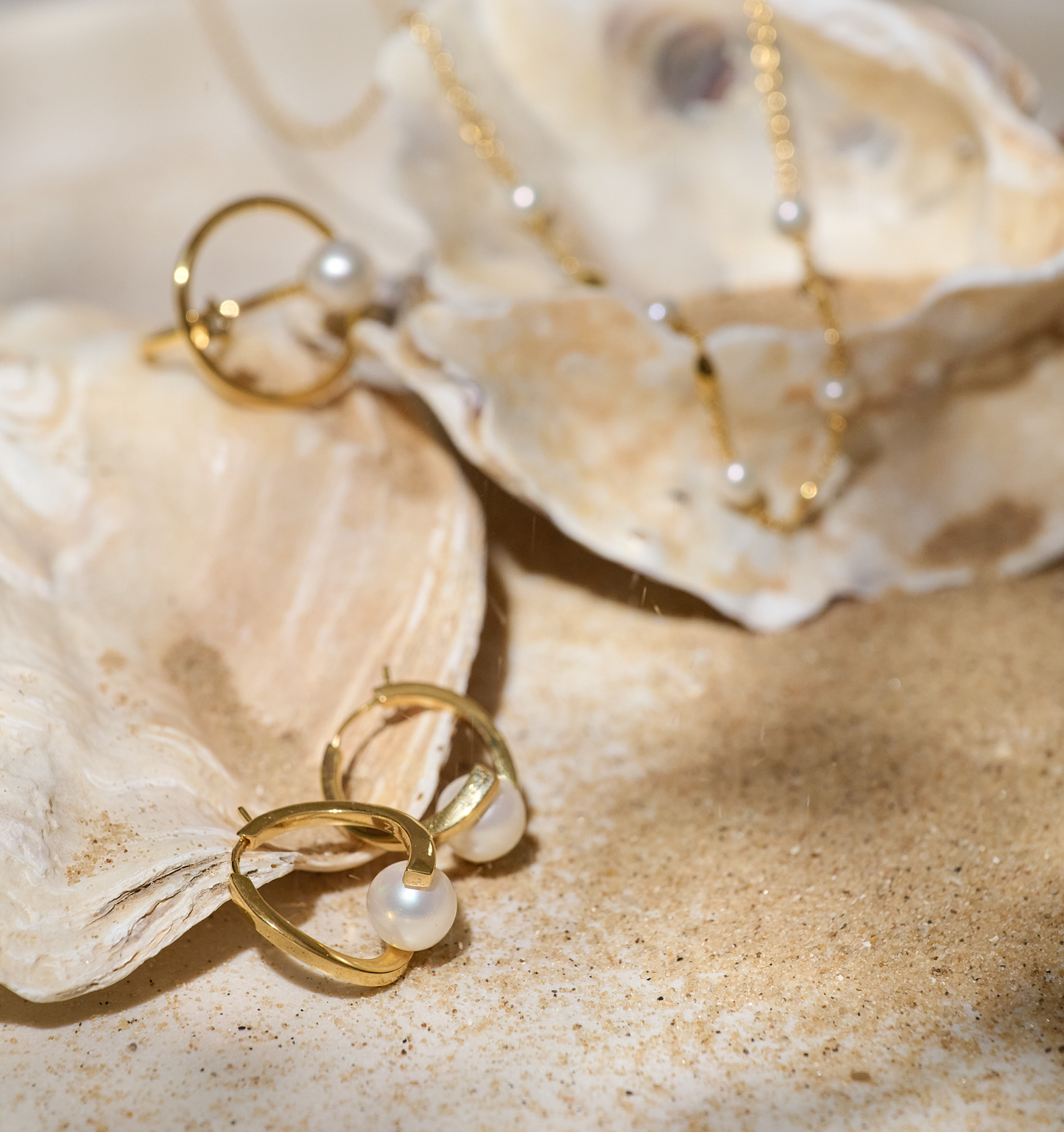 Sharvani Earrings gold hoops with pearls on sandy seashell background